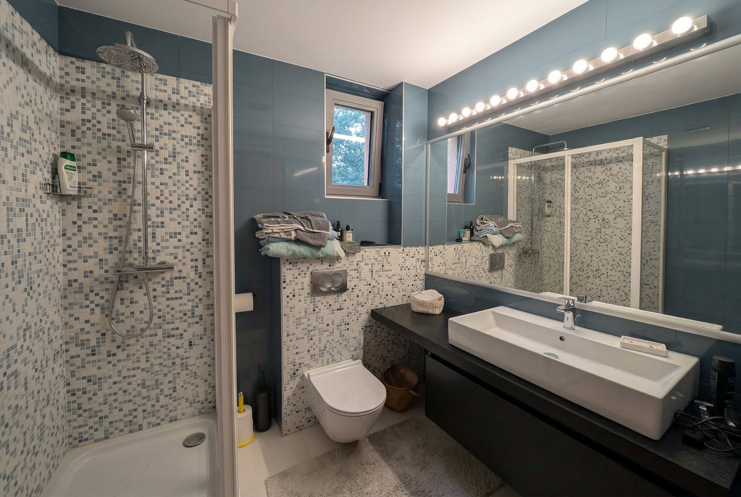 Modern bathroom in an apartment in Bečići, Montenegro: shower cabin, mosaic tiles, and wall-mounted fixtures.
