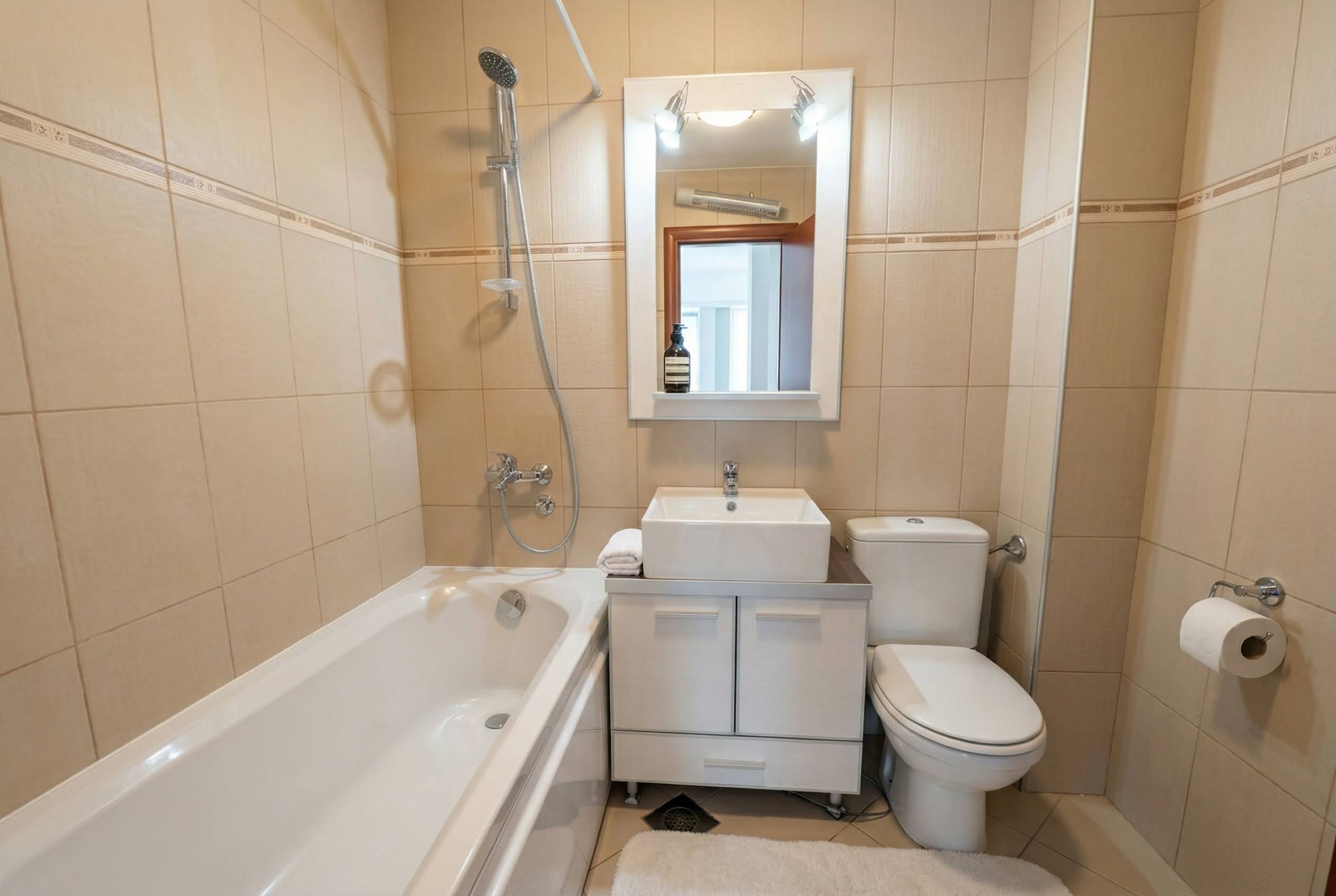 Bathroom with white sanitary ware and beige tiles in an apartment in Bečići, Montenegro. Modern interior.