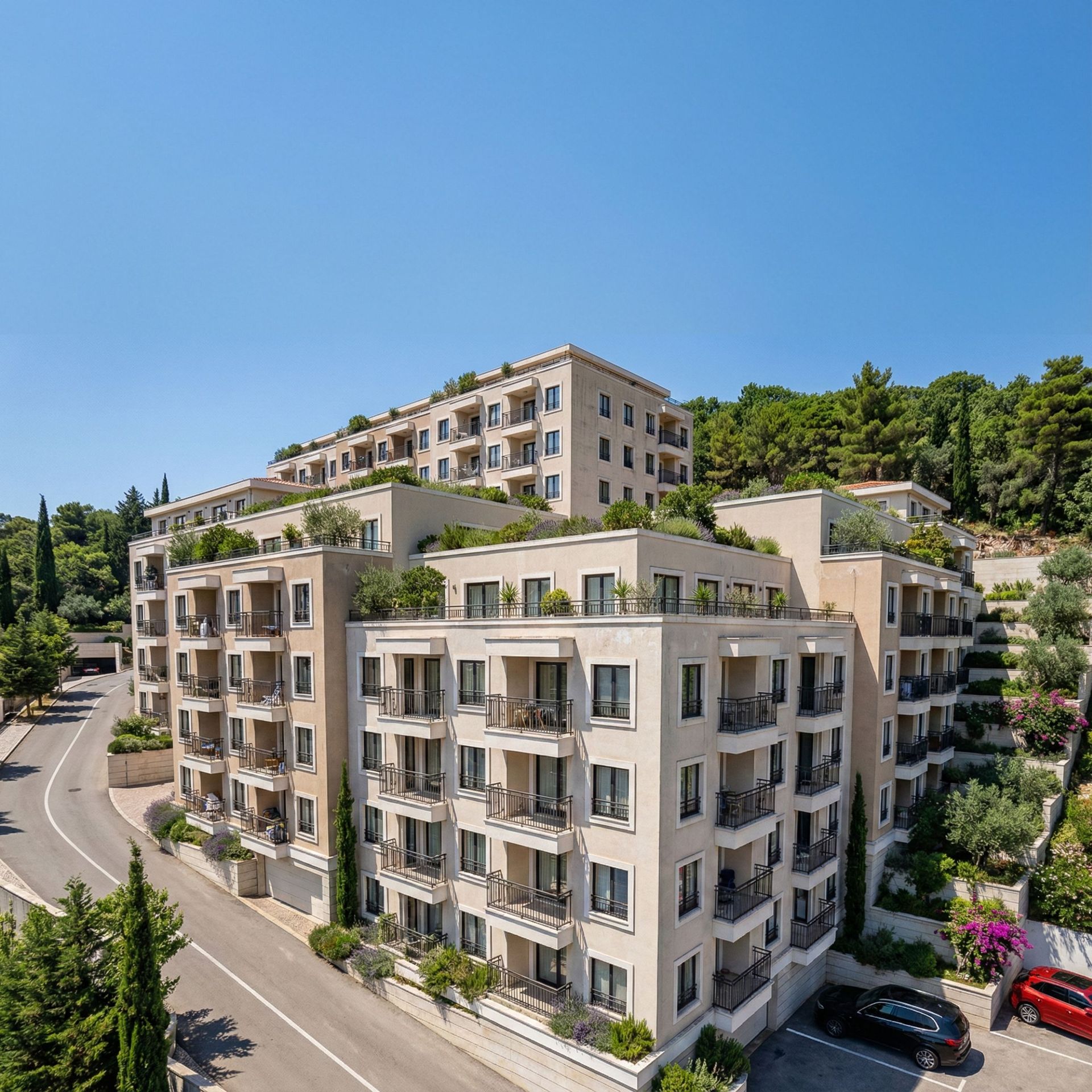 Modern residential complex with terraces and landscaping in Budva, Montenegro: view of the building facade and adjacent road.