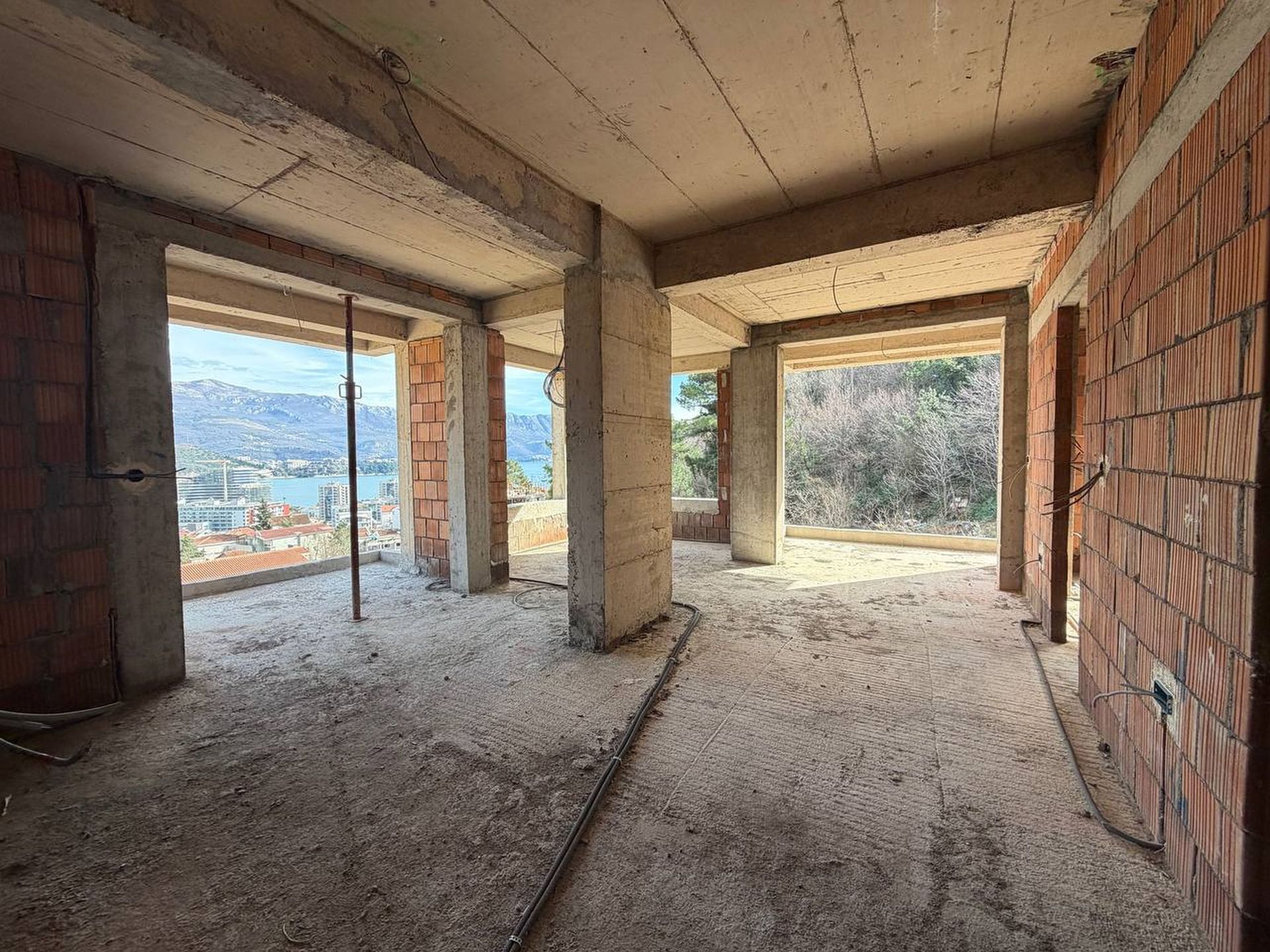 Living room unfinished in a residential complex under construction in Budva, Montenegro, with panoramic sea and mountain views.