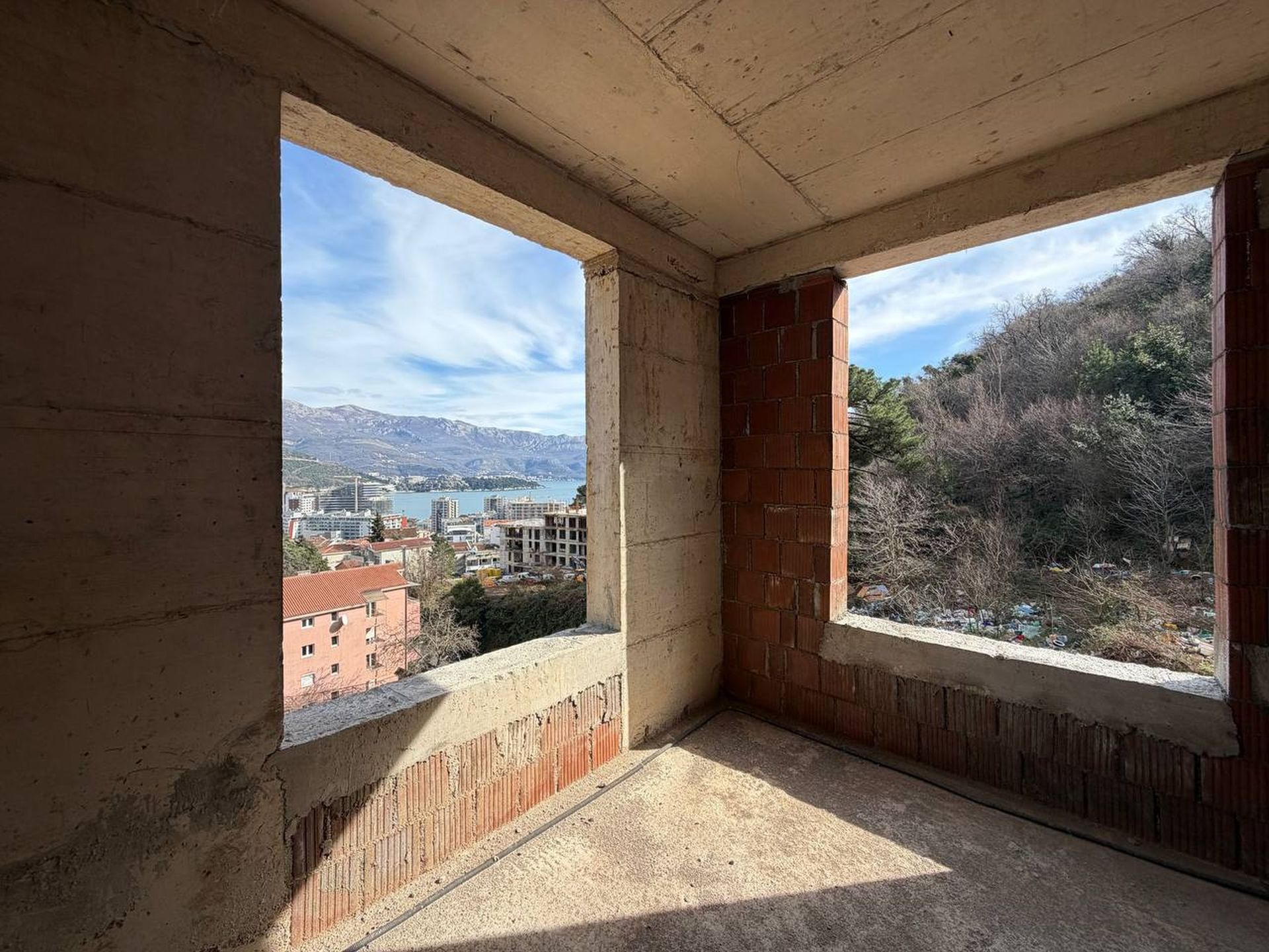 Unfinished balcony in a residential complex under construction in Budva, Montenegro, with panoramic sea and mountain views.