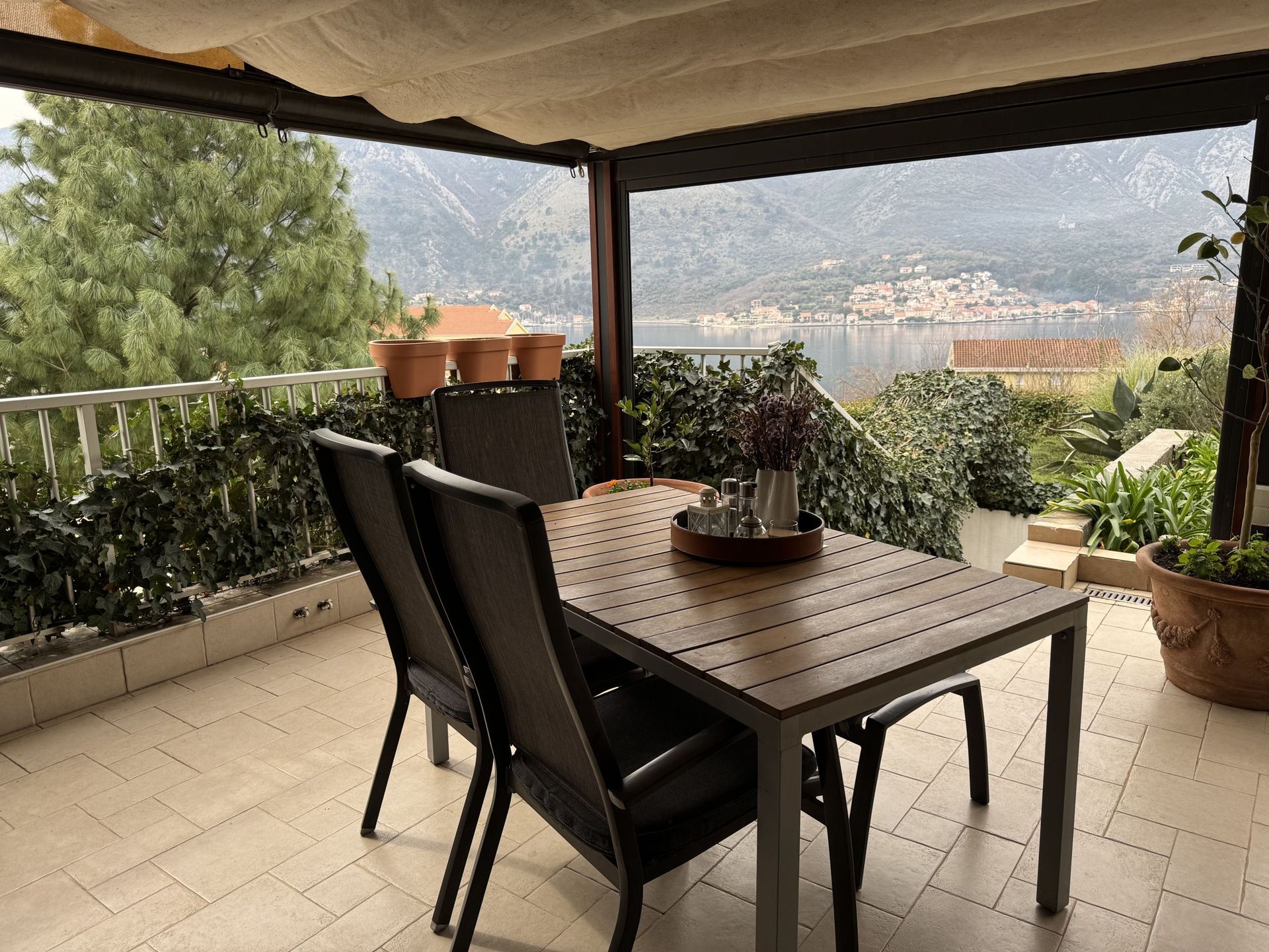 Terrace with a dining area and panoramic views of the Bay of Kotor and the mountains in Dobrota, Montenegro.