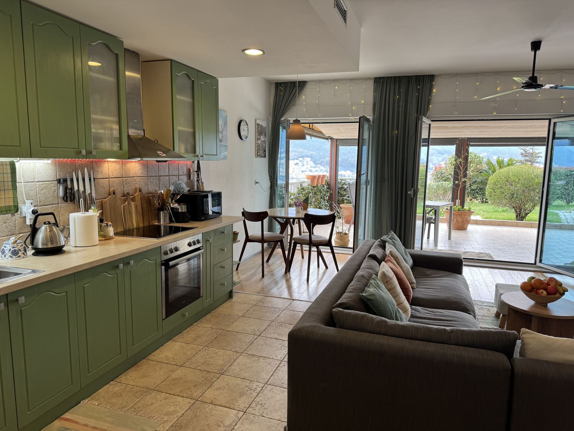 Kitchen-living room with green furniture and access to the terrace in an apartment, Dobrota, Montenegro.