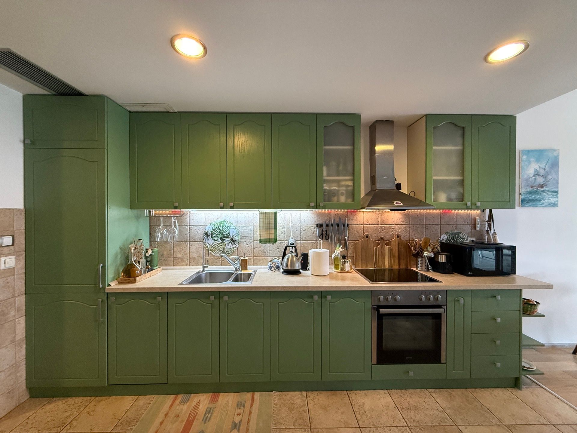 Modern green kitchen with built-in appliances in an apartment in Dobrota, Montenegro: stove, oven, and stylish interior.