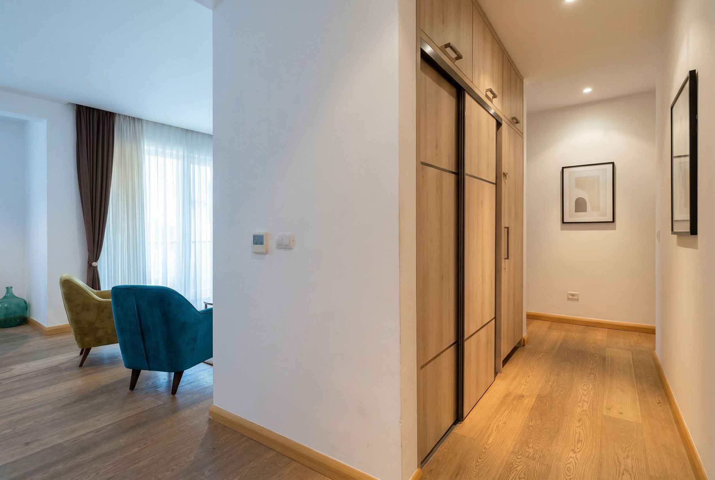 Modern living room in an apartment in Budva, Montenegro: built-in wardrobe, parquet flooring, and bright armchairs in the interior.