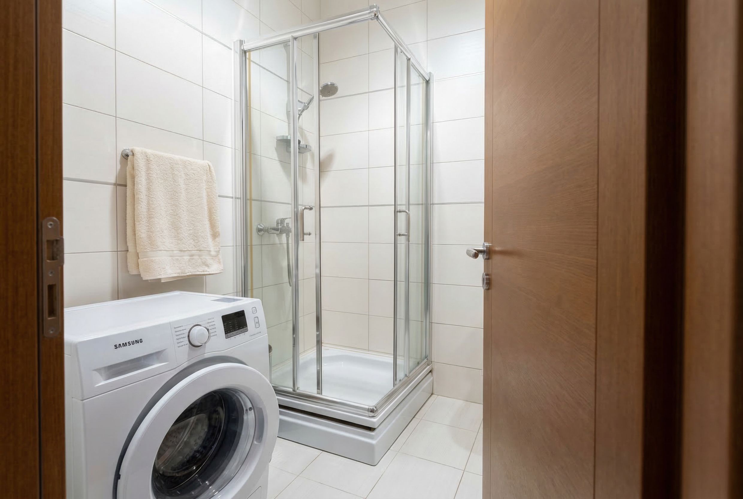 Bathroom in a penthouse in Kamenovo, Montenegro: shower cabin, Samsung washing machine, and light finishes.