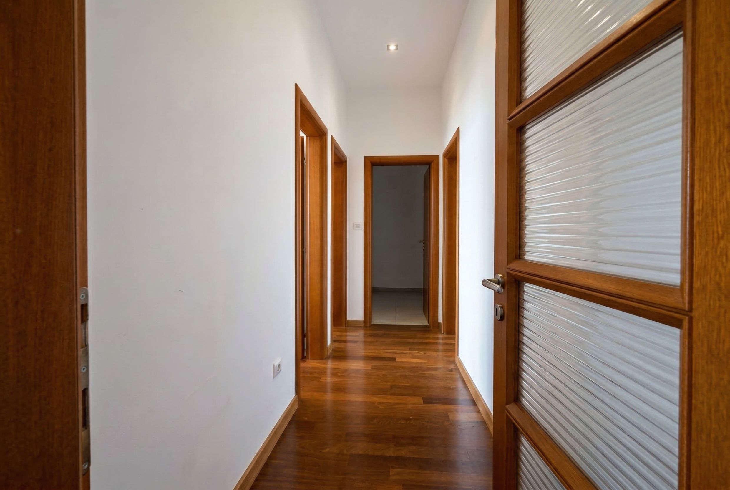 Bright hallway in a penthouse in Kamenovo, Montenegro: wooden floor, solid wood interior doors, and white walls.