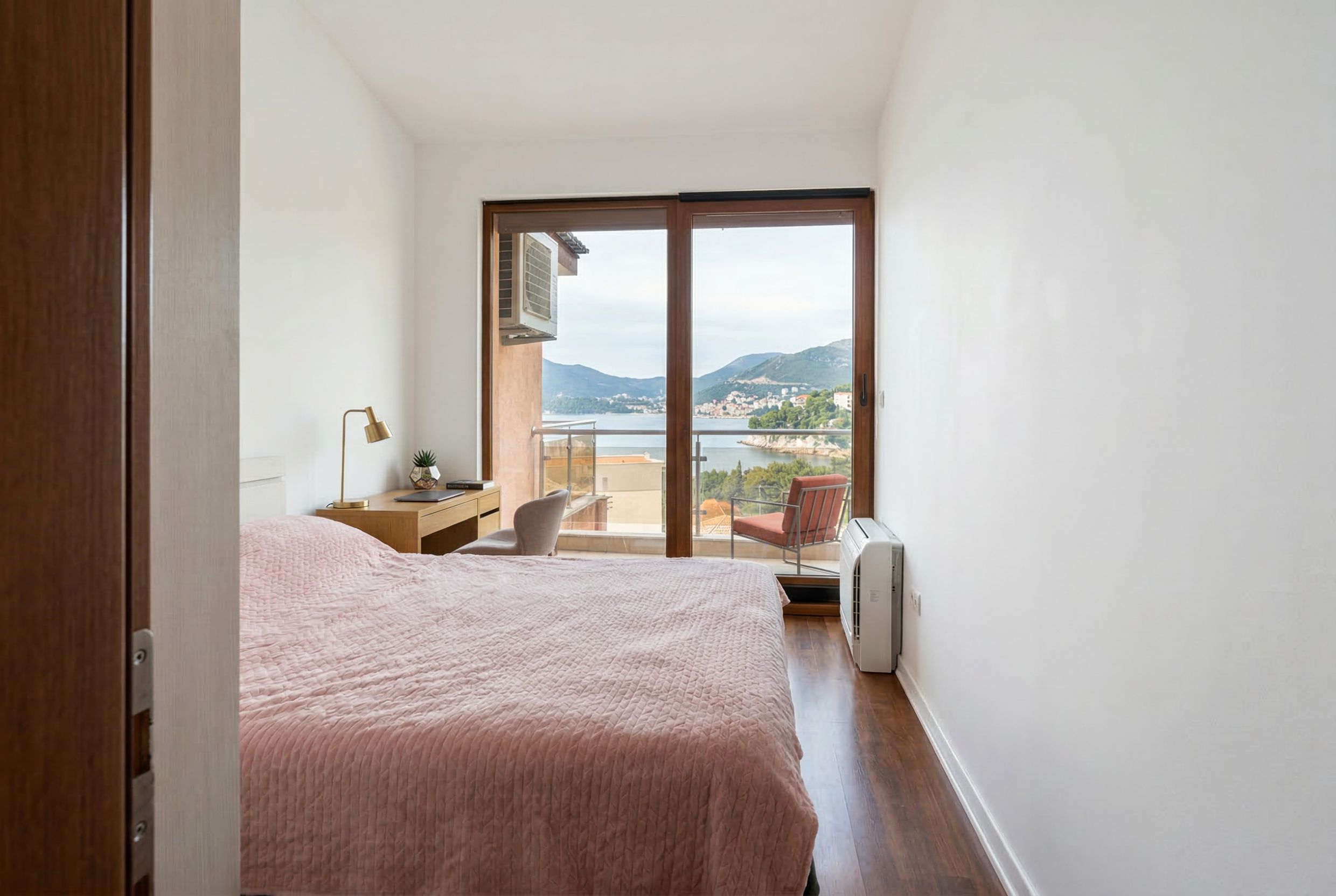 Bedroom with a double bed and sea view in a penthouse, Kamenovo, Montenegro. Panoramic windows and a balcony.