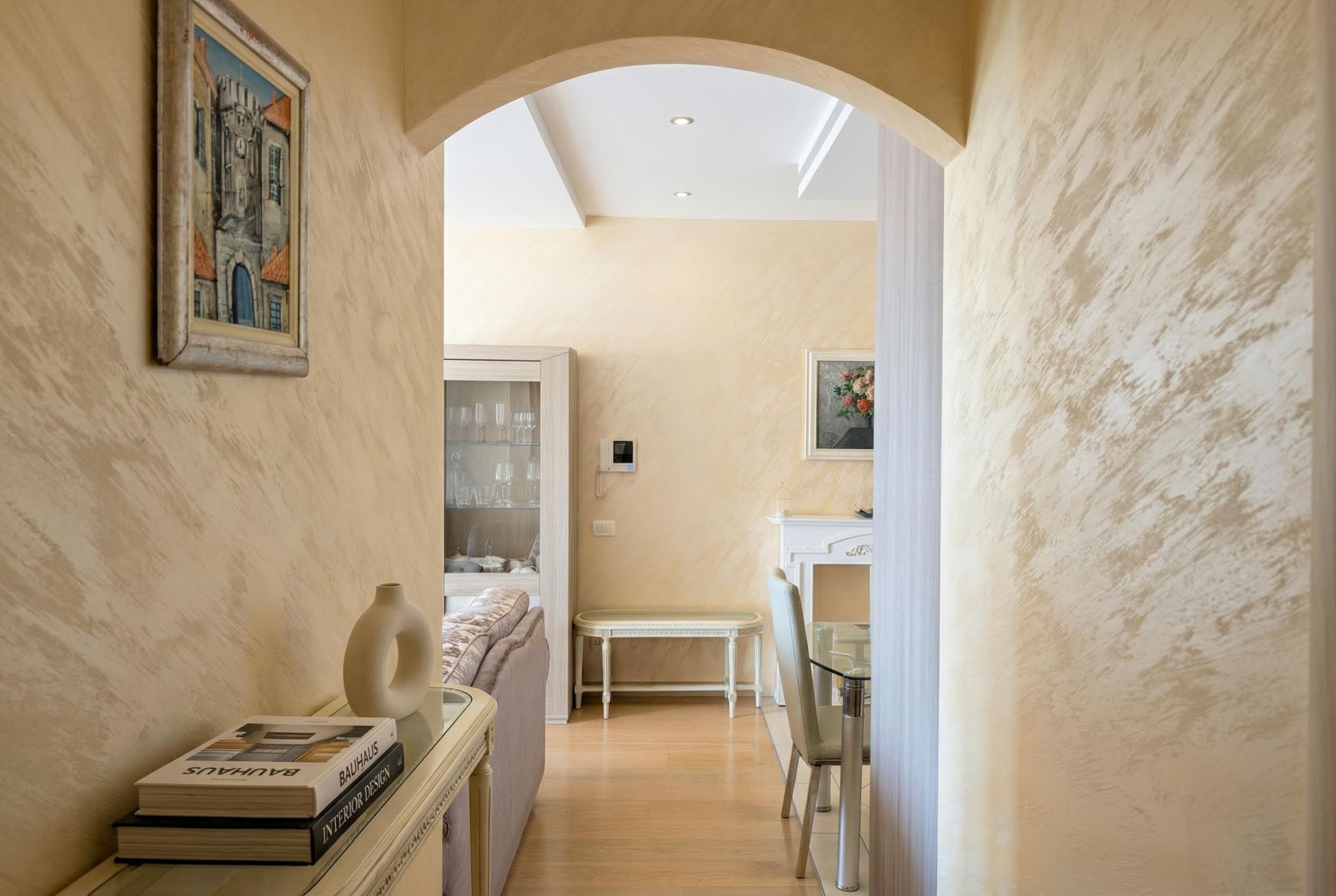 Living room interior in an apartment in Bečići, Montenegro: arched passageway, decorative plaster, and light-colored furniture.