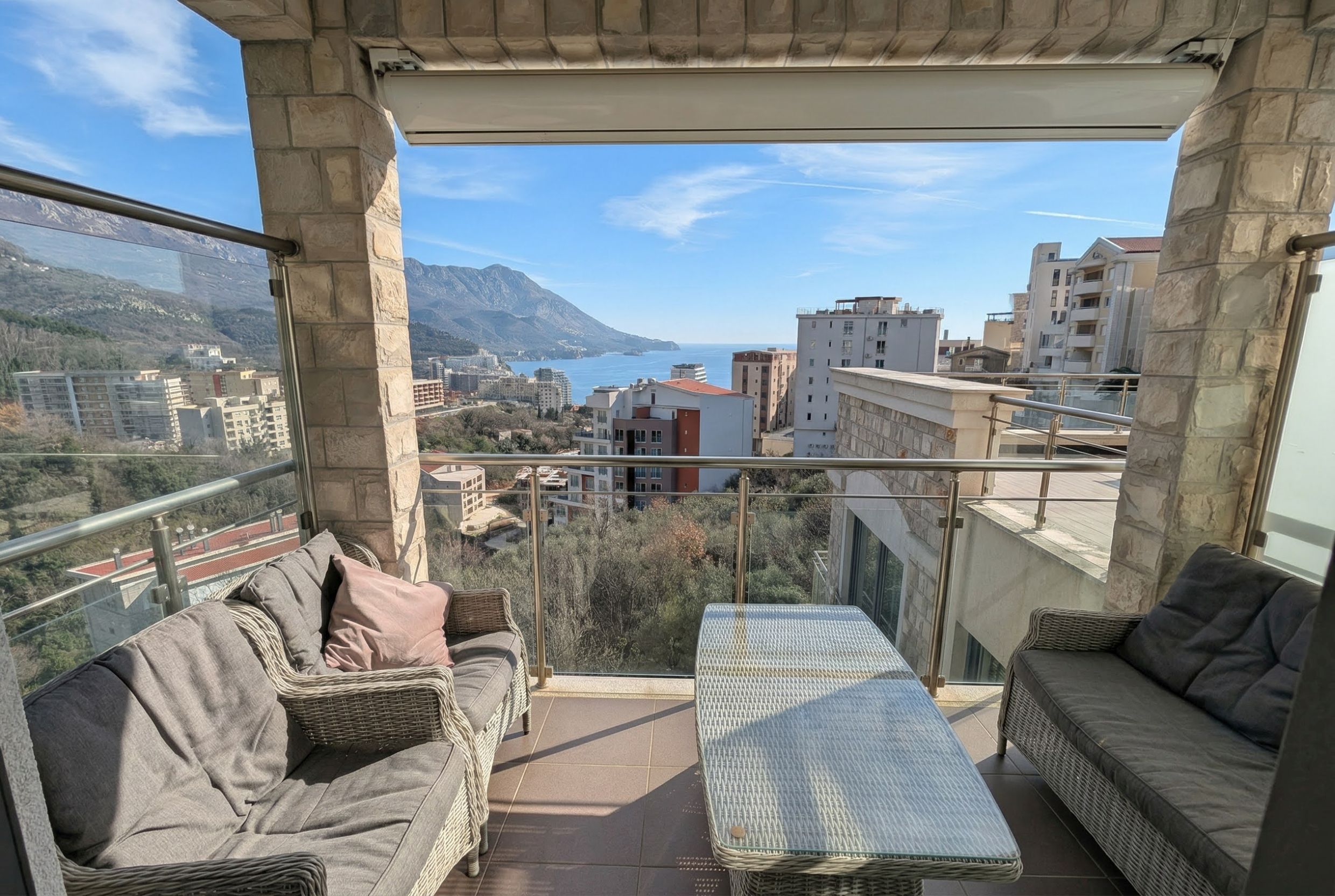 Terrace with wicker furniture and panoramic views of the sea and mountains in an apartment, Becici, Montenegro.