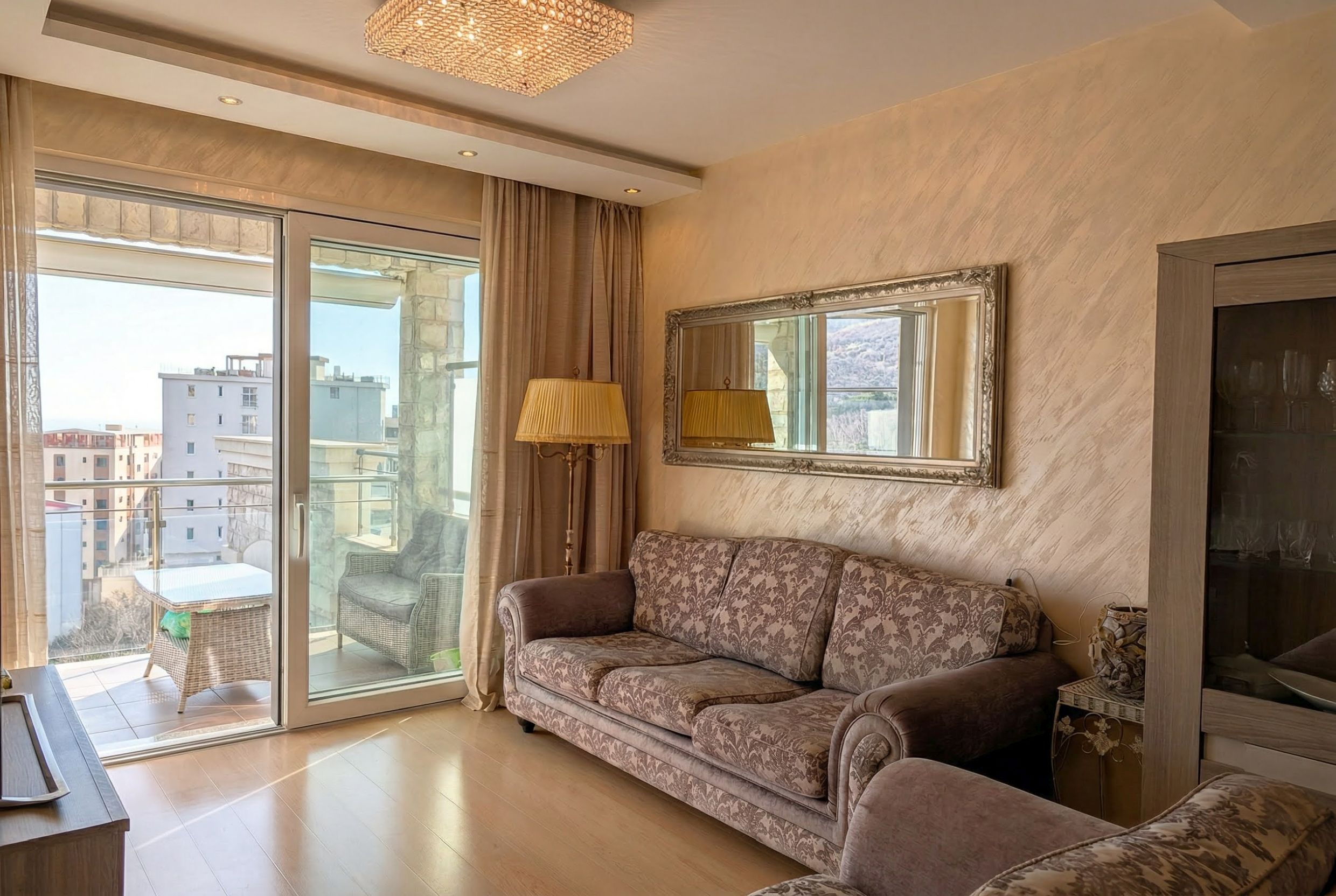 Living room with classic furniture and access to the terrace in an apartment in Bečići, Montenegro. City and mountain view.