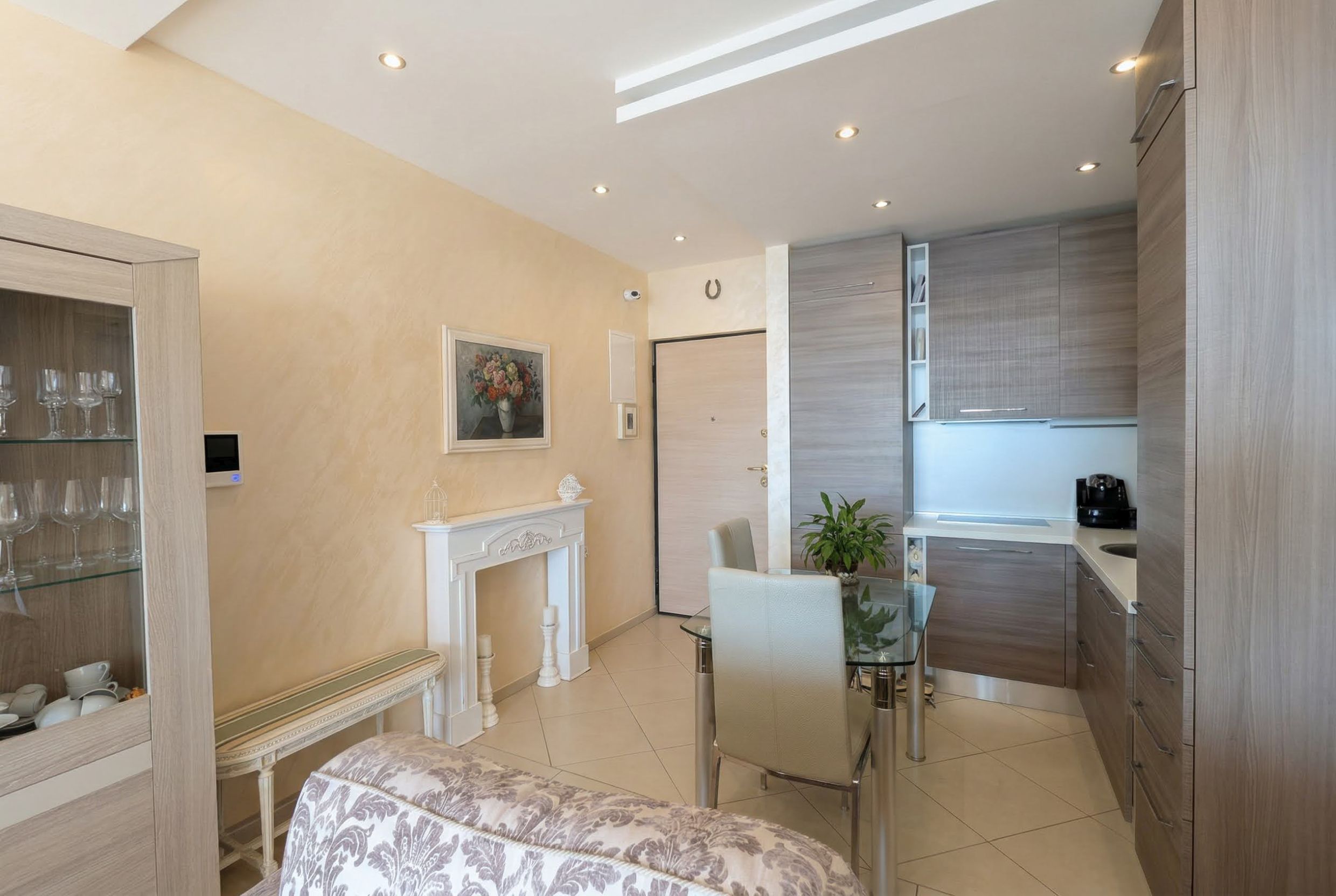 Living room with kitchen in an apartment in Bečići, Montenegro: modern furniture, decorative fireplace, and dining area.