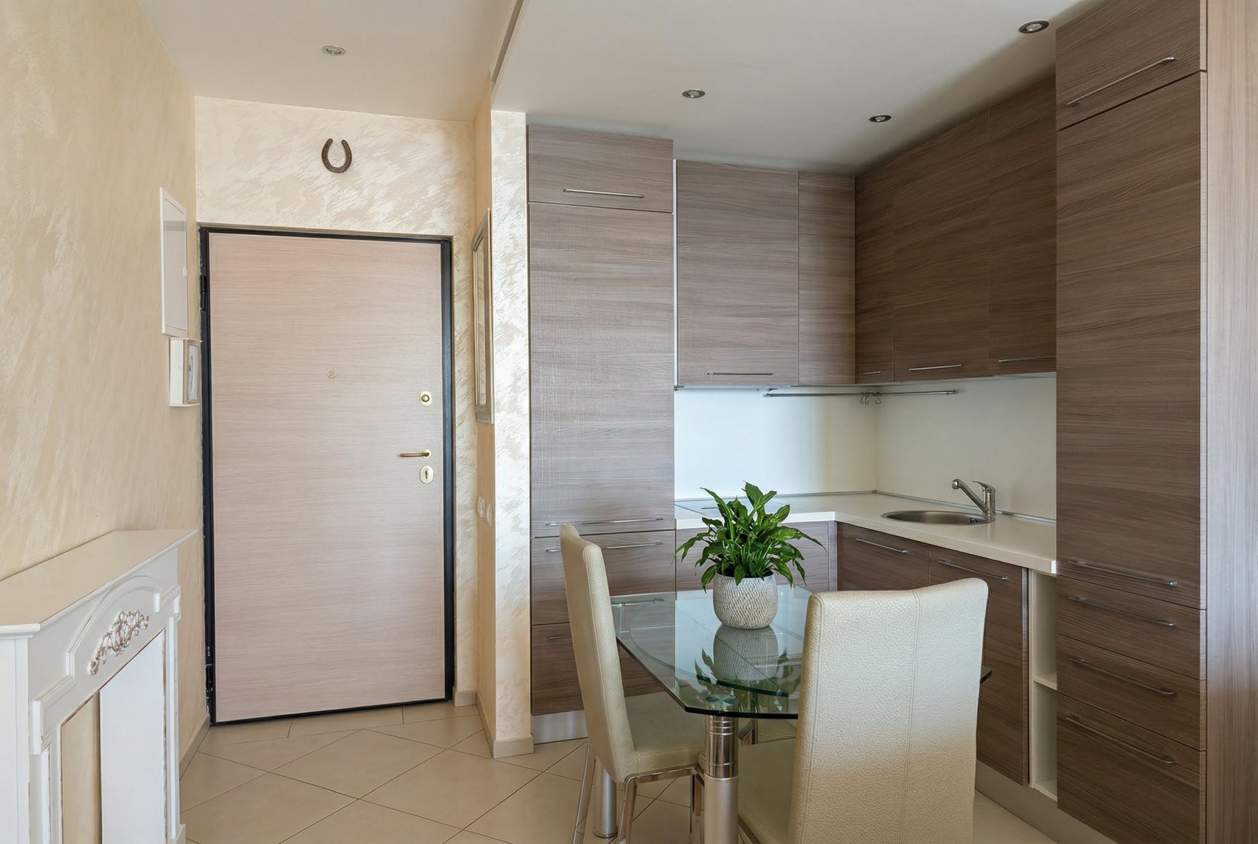 Modern kitchen in an apartment in Bečići, Montenegro: wood-finish cabinets, glass table, and light wall finishes.