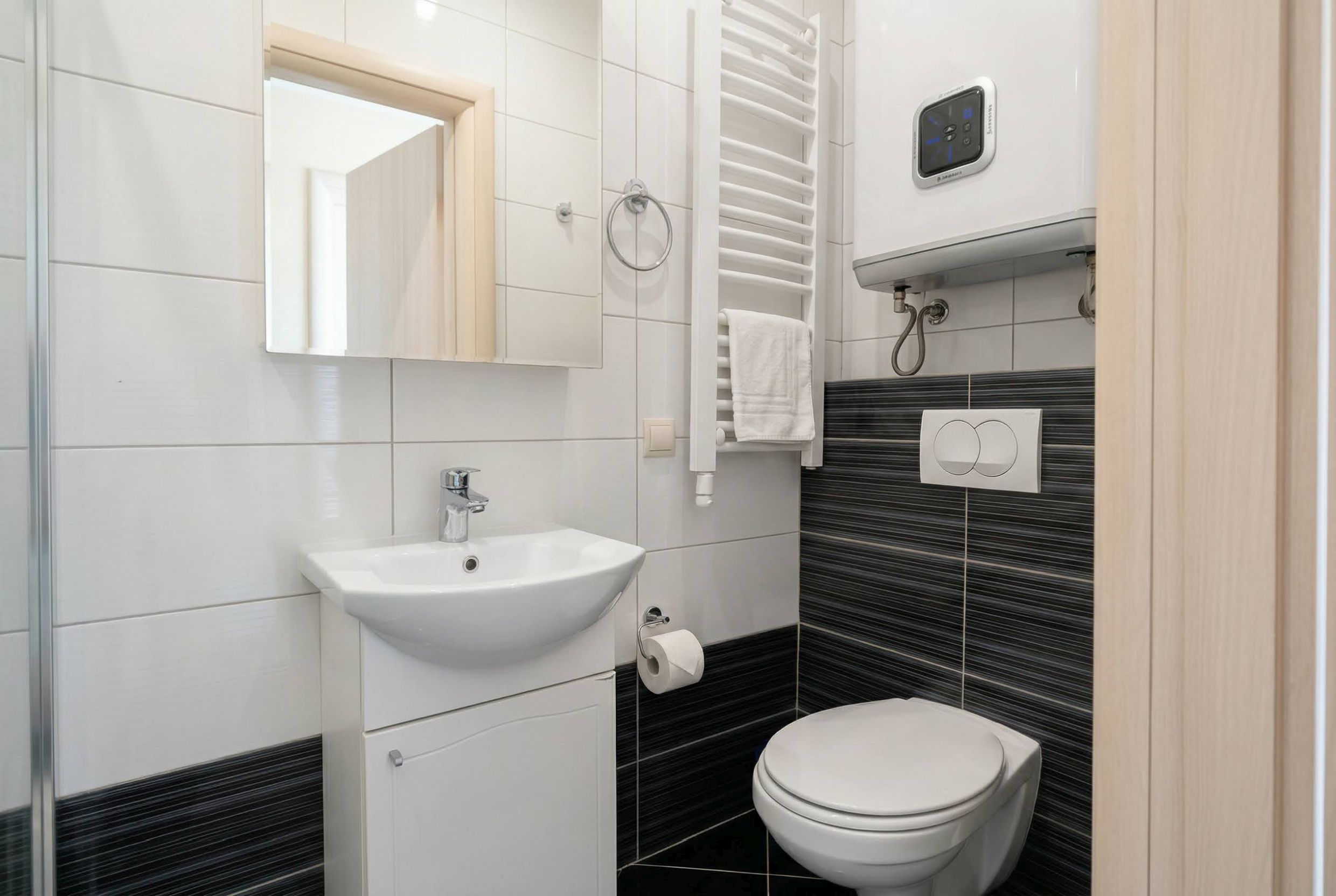 Modern bathroom in an apartment, Becici, Montenegro: white fixtures, towel warmer, and stylish tiles.