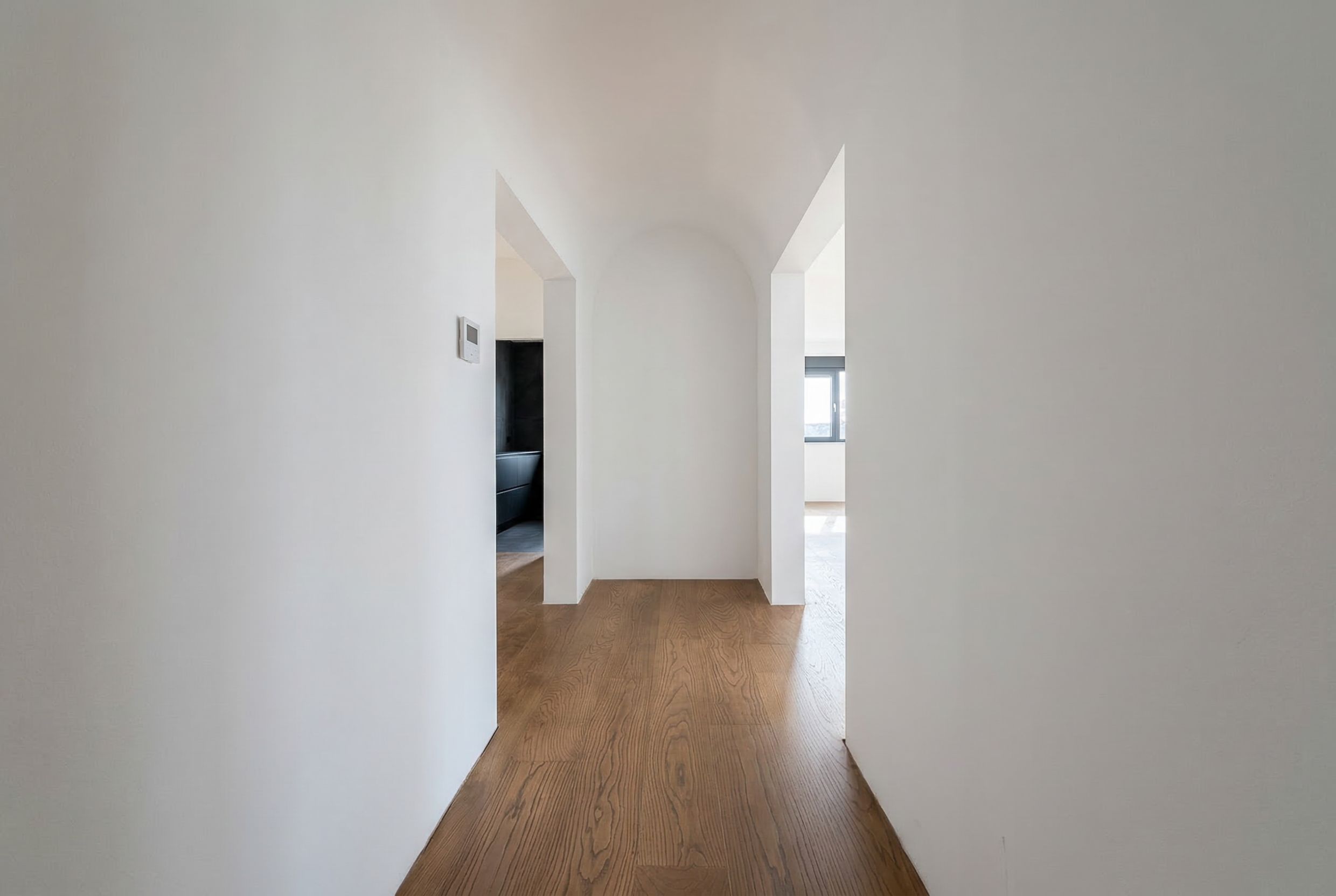 Bright hallway with an arched doorway and wooden flooring in a penthouse, Budva, Montenegro. Modern apartment interior.