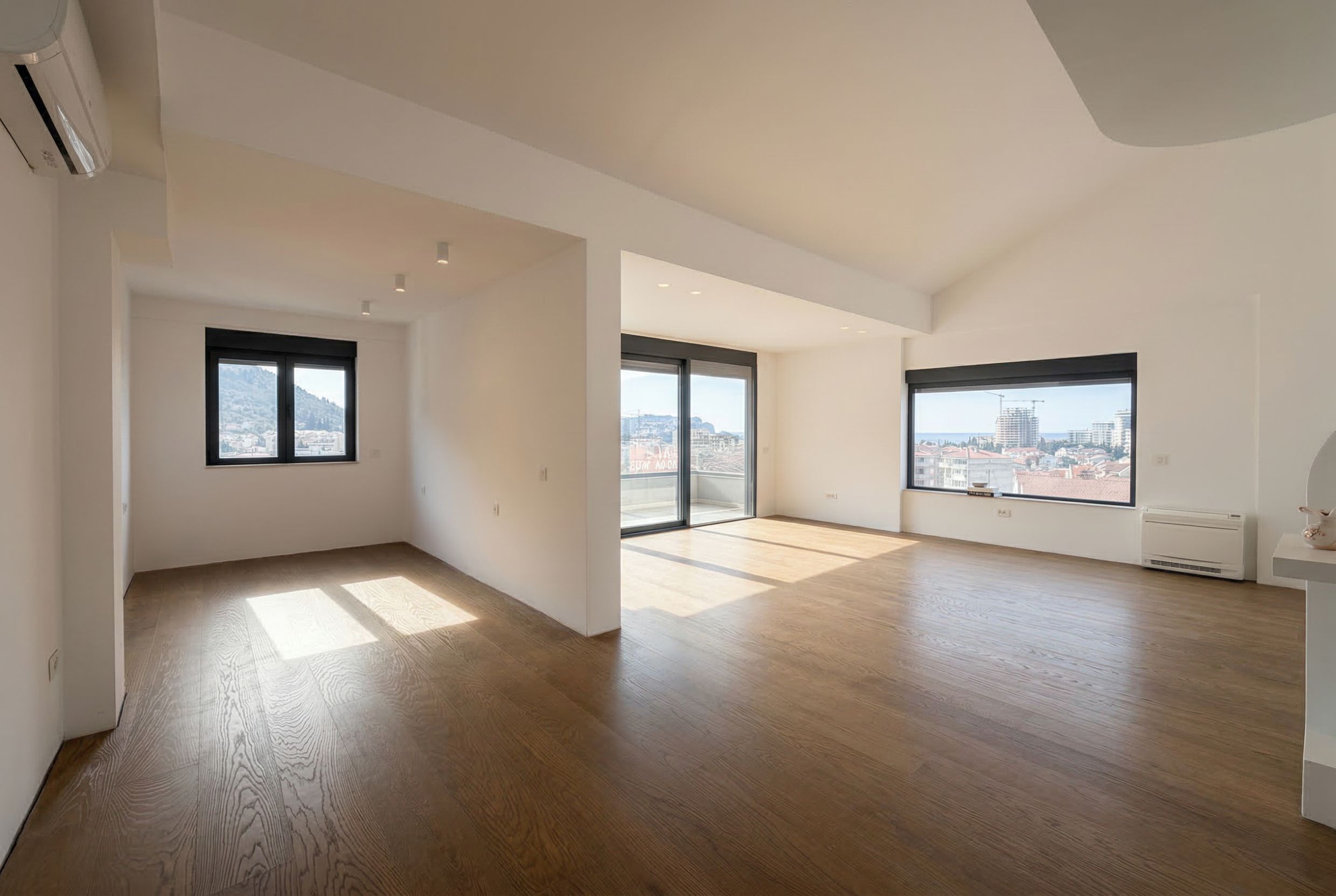 Spacious and bright living room in a penthouse, Budva, Montenegro: panoramic windows, parquet flooring, and access to the terrace.