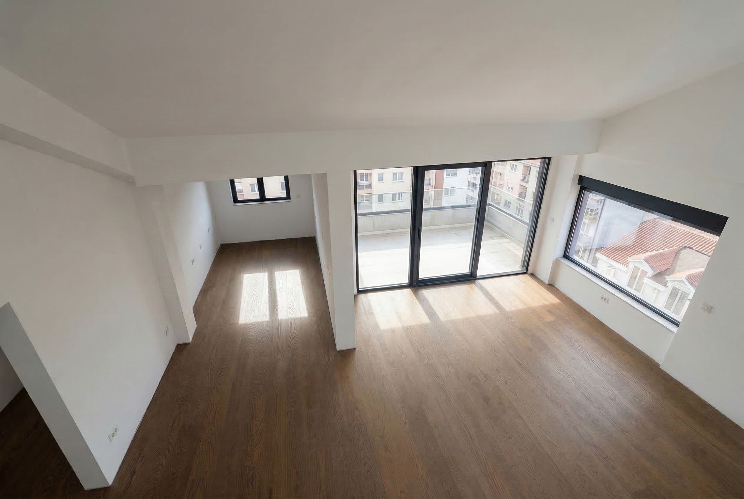 Bright living room in a penthouse in Budva, Montenegro: panoramic windows, access to the terrace, and parquet flooring.