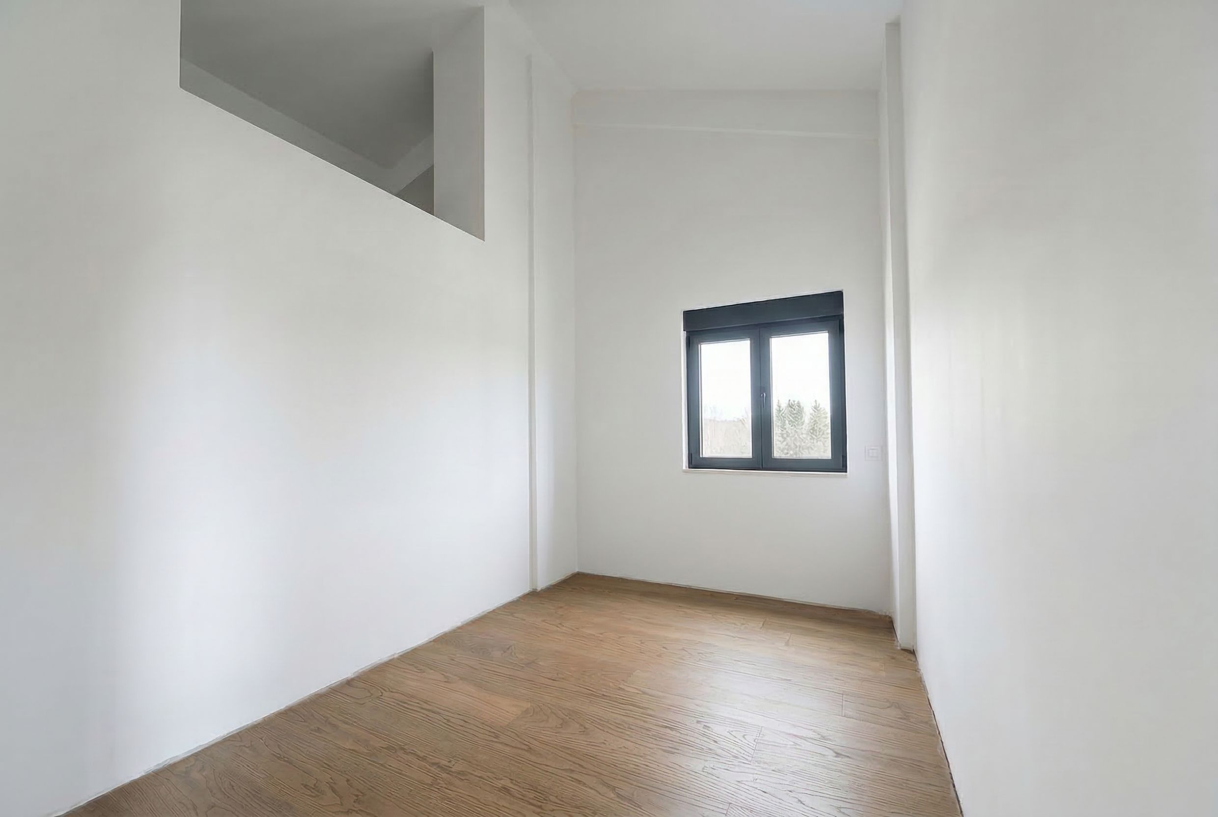Bright bedroom with high ceilings and parquet flooring in a penthouse, Budva, Montenegro. Modern finishes, view from the window.