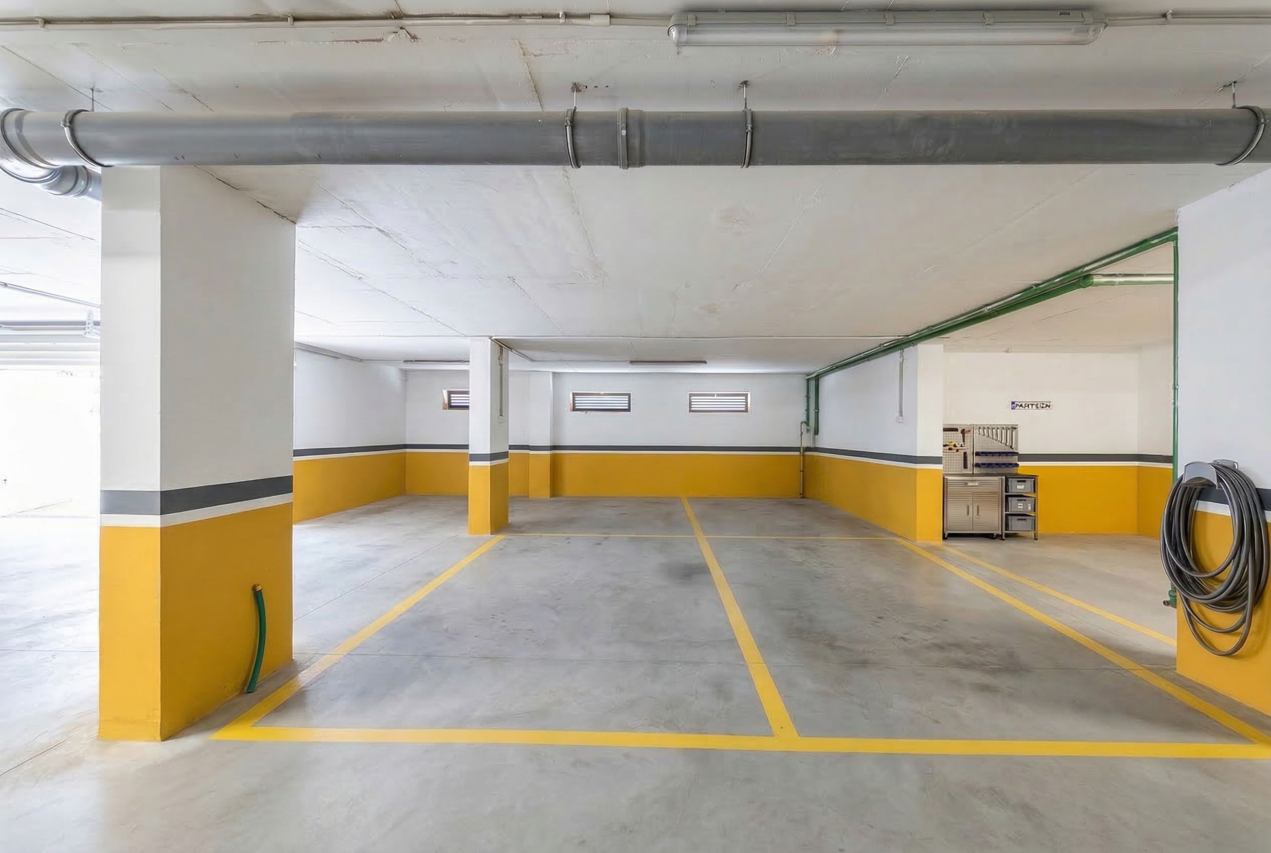 Spacious indoor parking with marked spaces in a residential complex, Budva, Montenegro. Car space with an integrated storage area for tools.