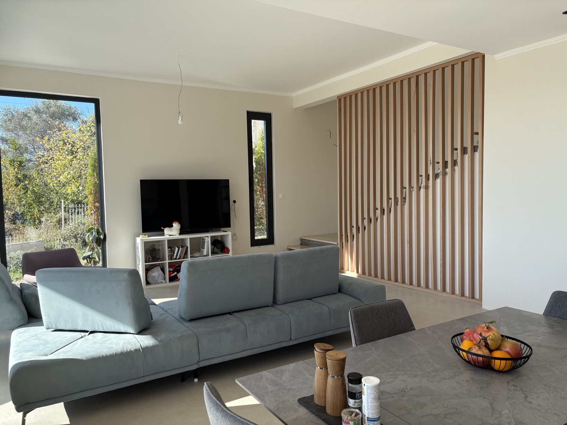 Modern living room with a gray sofa and wooden partition in a villa, Herceg Novi, Montenegro.