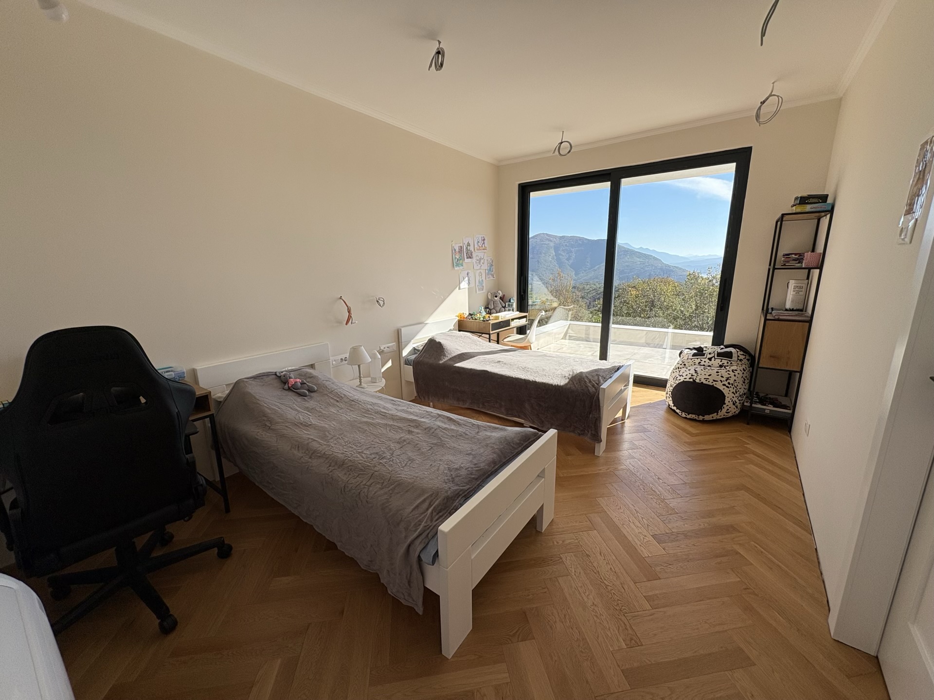 Children's bedroom with two beds, parquet flooring, and panoramic mountain views in the Herceg Novi residential complex, Montenegro.
