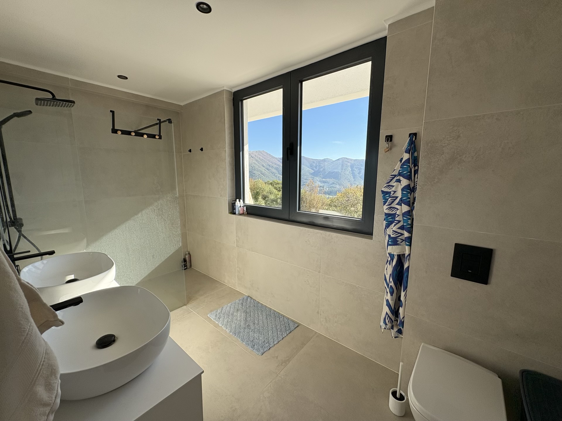 Modern bathroom with mountain views in a residential complex, Herceg Novi, Montenegro: two sinks and a shower cabin.