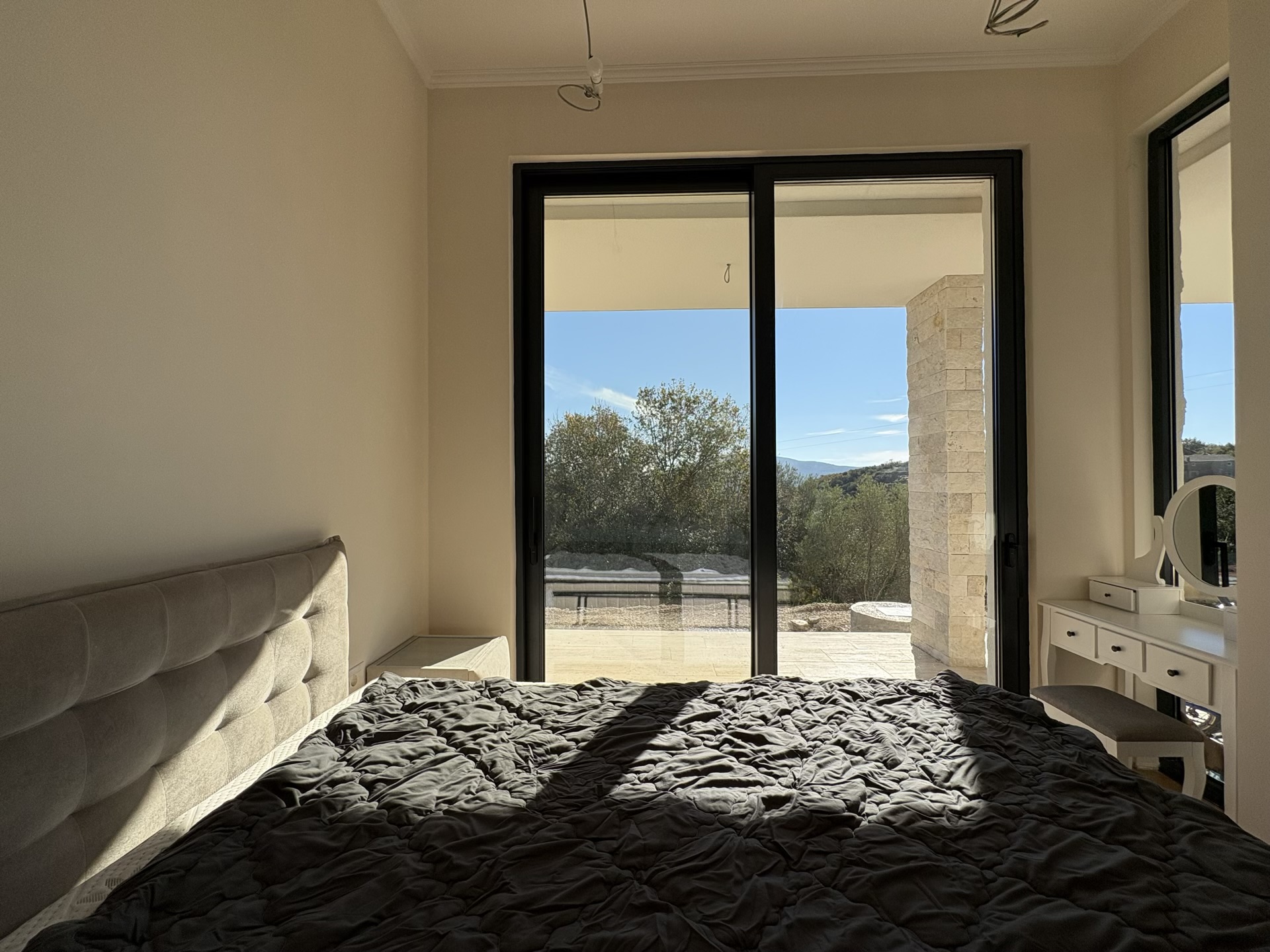 Bedroom in a villa complex in Herceg Novi, Montenegro: panoramic windows, access to the terrace, a double bed and a dressing table...