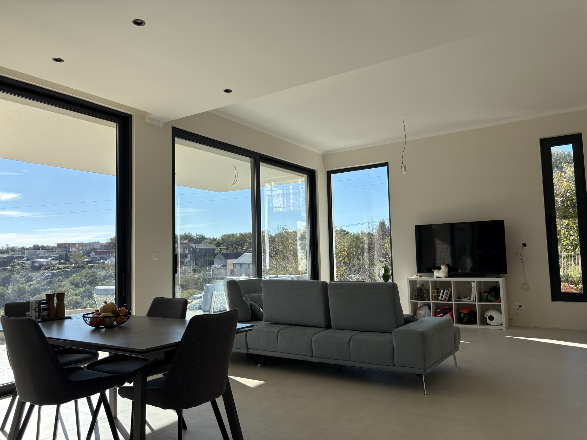Modern living room with panoramic windows and a view of Herceg Novi, Montenegro: stylish furniture and a bright interior.