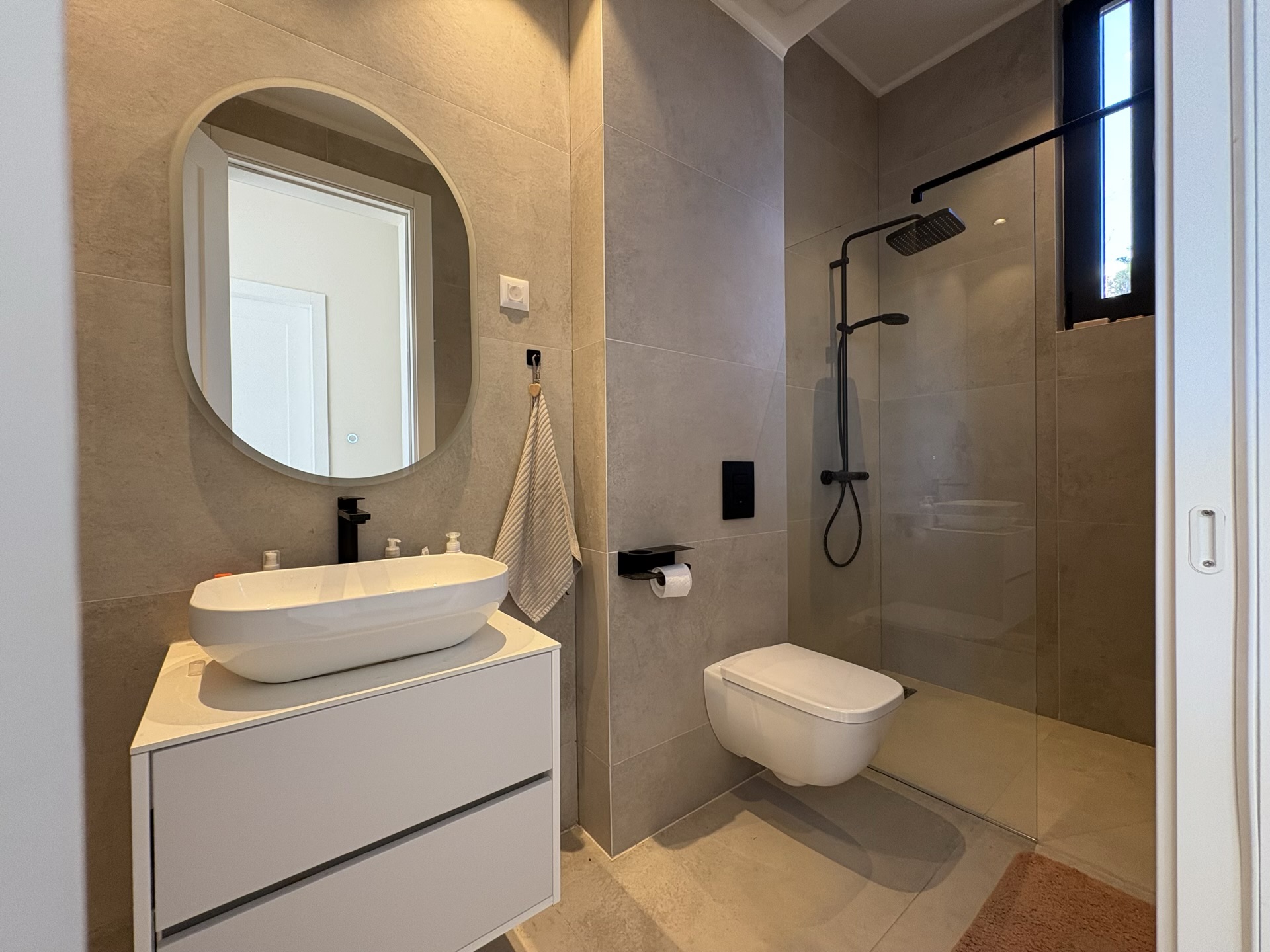 Modern bathroom in a villa complex, Herceg Novi, Montenegro: shower cabin, wall-hung toilet, and vanity cabinet.