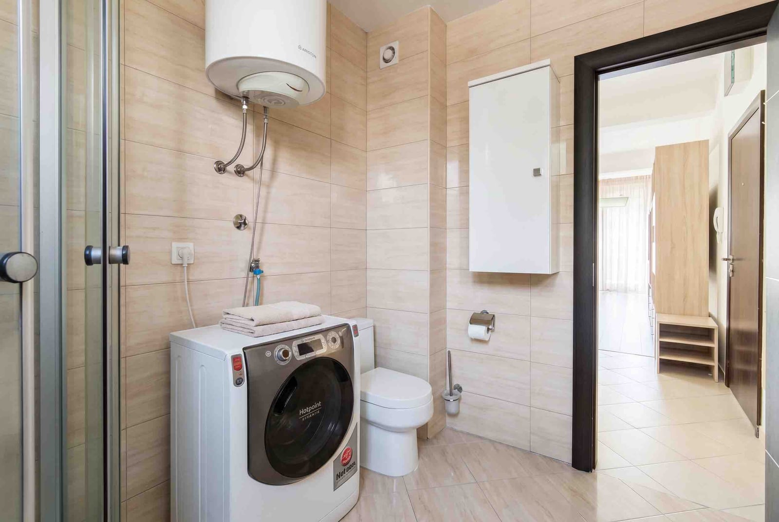 Modern bathroom in an apartment in Bečići, Montenegro: walk-in shower, washing machine, and Ariston water heater.