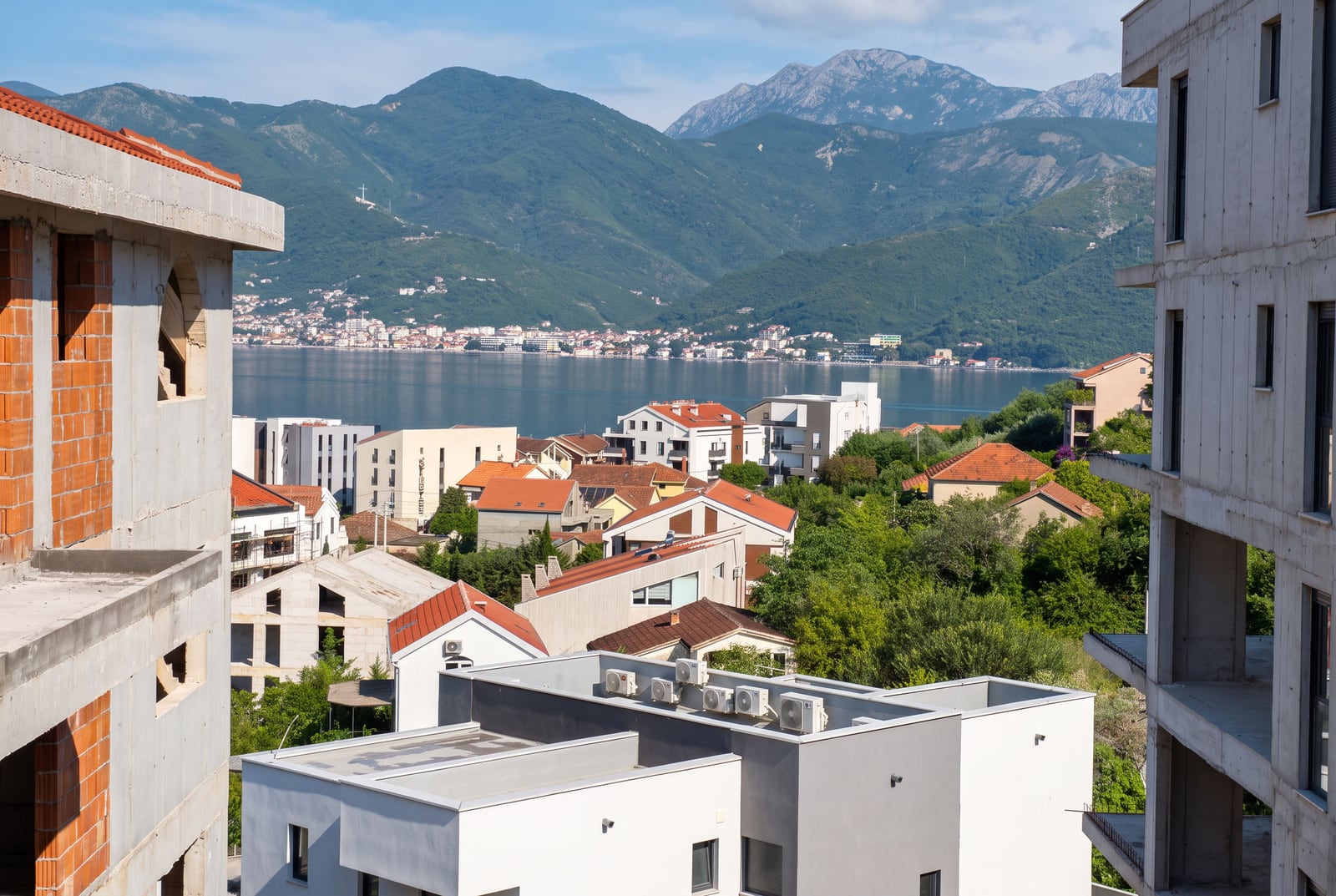 View of a coastal town and mountains from an unfinished building exterior.