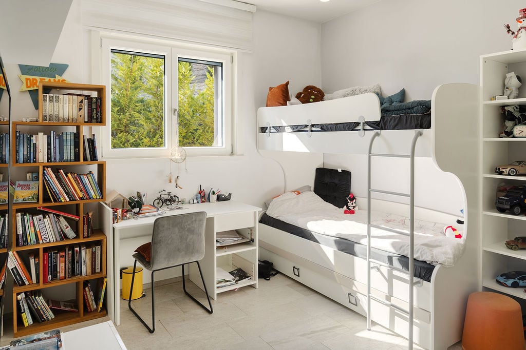 Children's bedroom with a bunk bed and a desk in a townhouse, Luštica, Montenegro. Bright interior with a bookshelf...