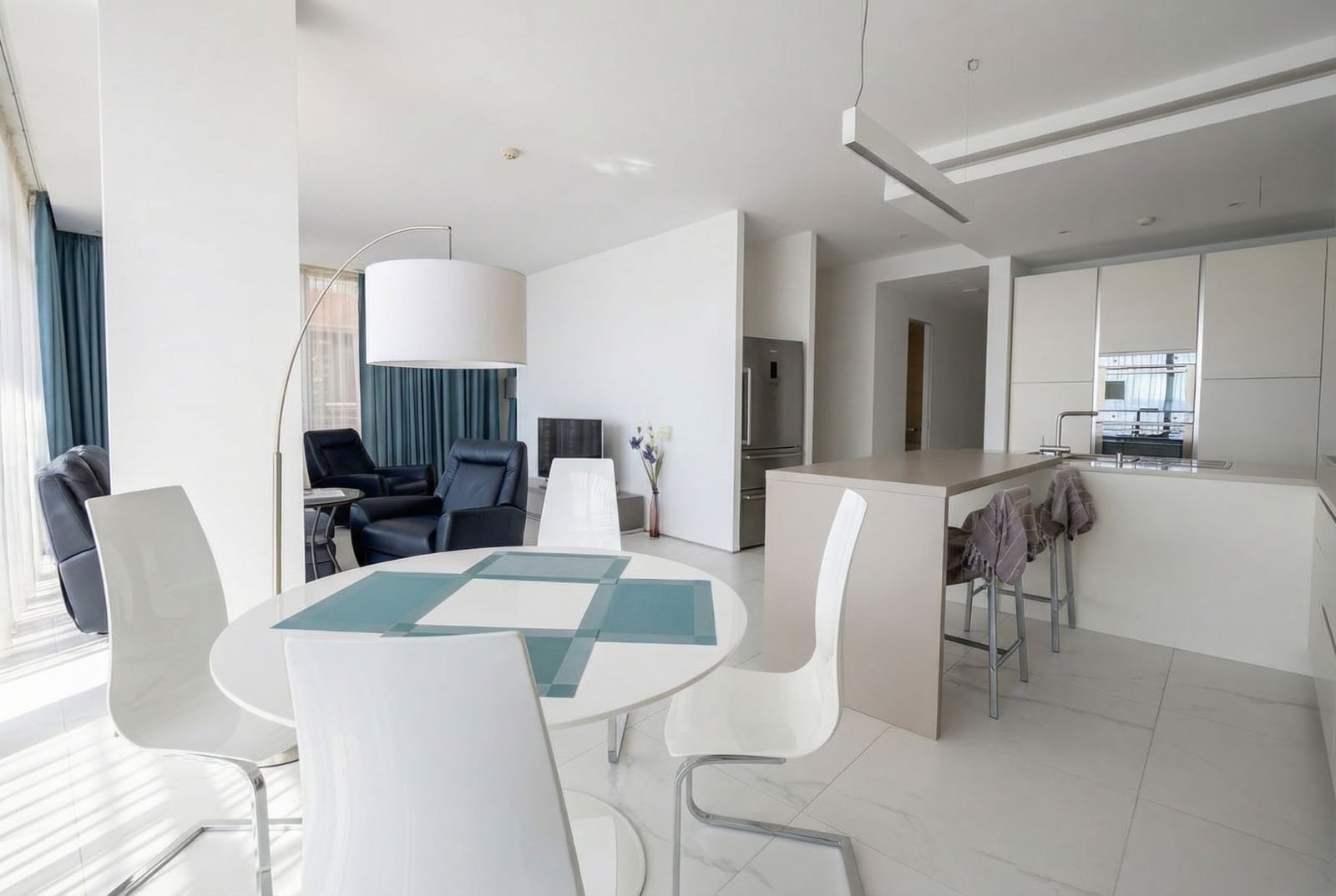 Modern living room with kitchen in Dukley apartments, Budva, Montenegro: white furniture, dining area, and sea view.
