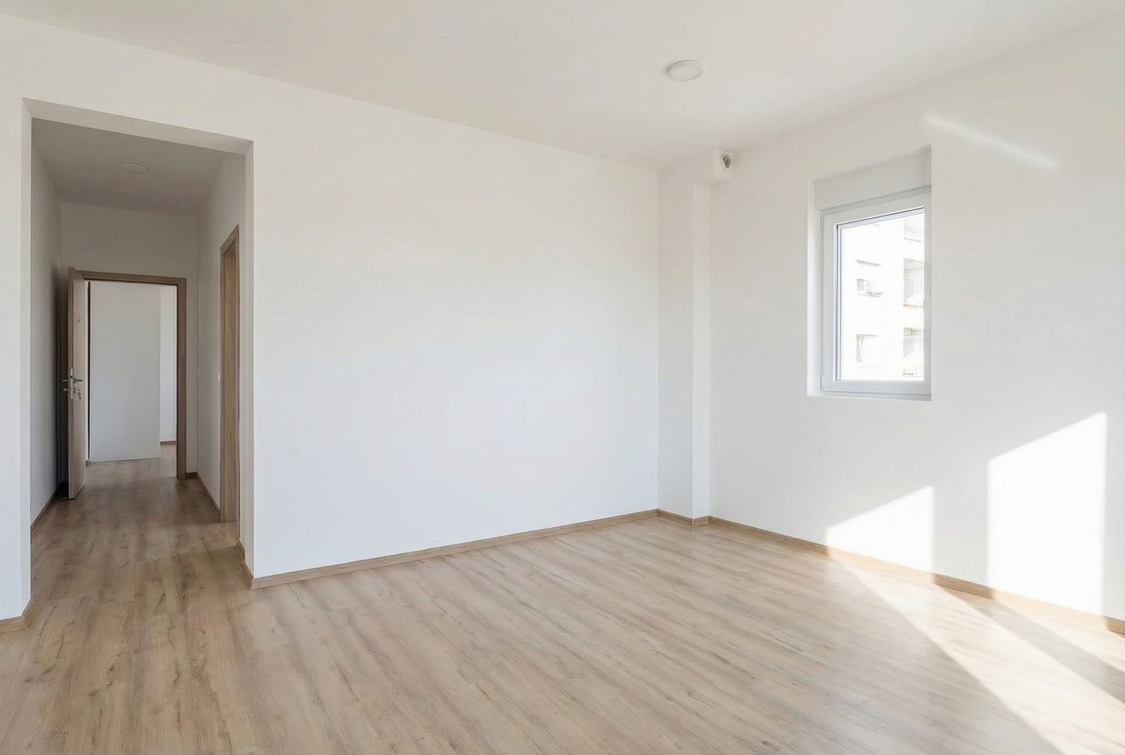 Bright empty living room with laminate flooring and white walls in an apartment, Budva, Montenegro. Modern interior finishes.