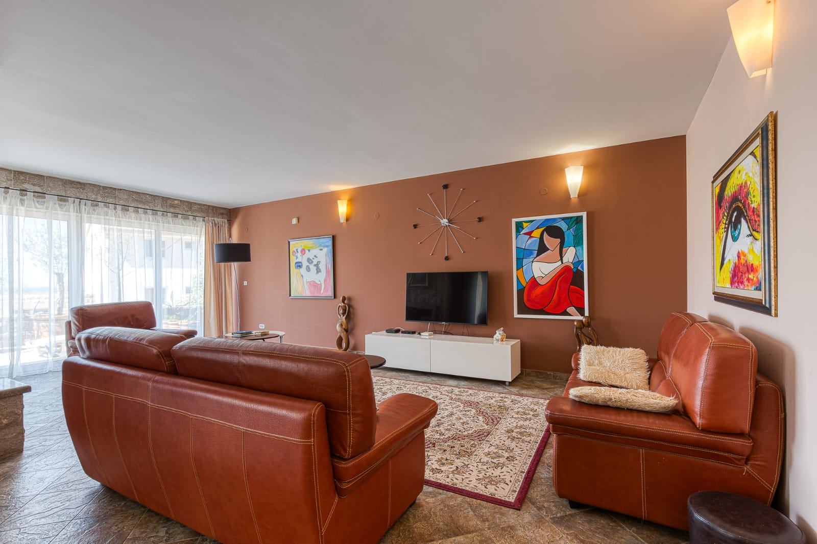 Living room with leather sofas in a villa in Bečići, Montenegro: stylish interior, panoramic windows, and wall decor.