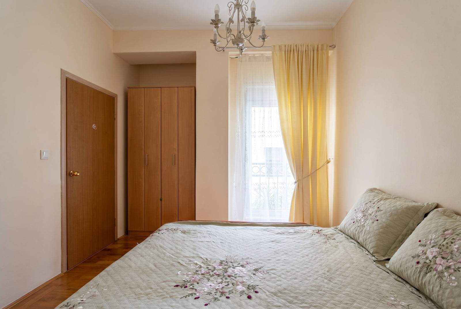 Cozy bedroom with a double bed, wardrobe, and chandelier in an apartment in Budva, Montenegro.