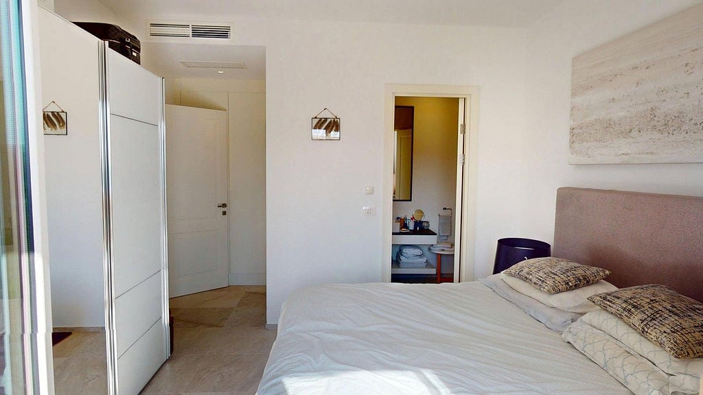 Bright bedroom with a double bed and built-in wardrobe in the Luštica apartments, Montenegro.