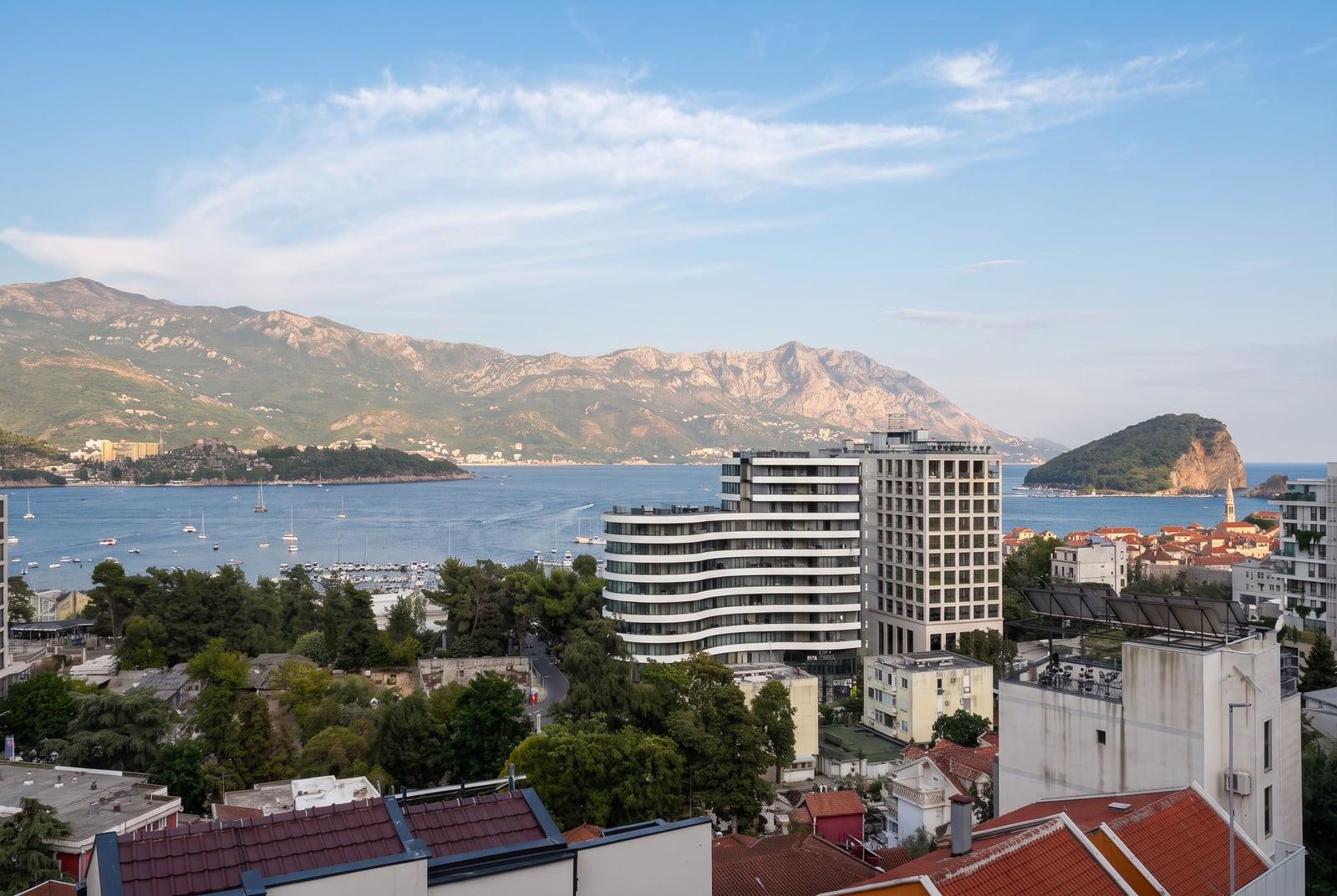 Panoramic view of the sea, marina, and mountains from the balcony of an apartment in Budva, Montenegro.