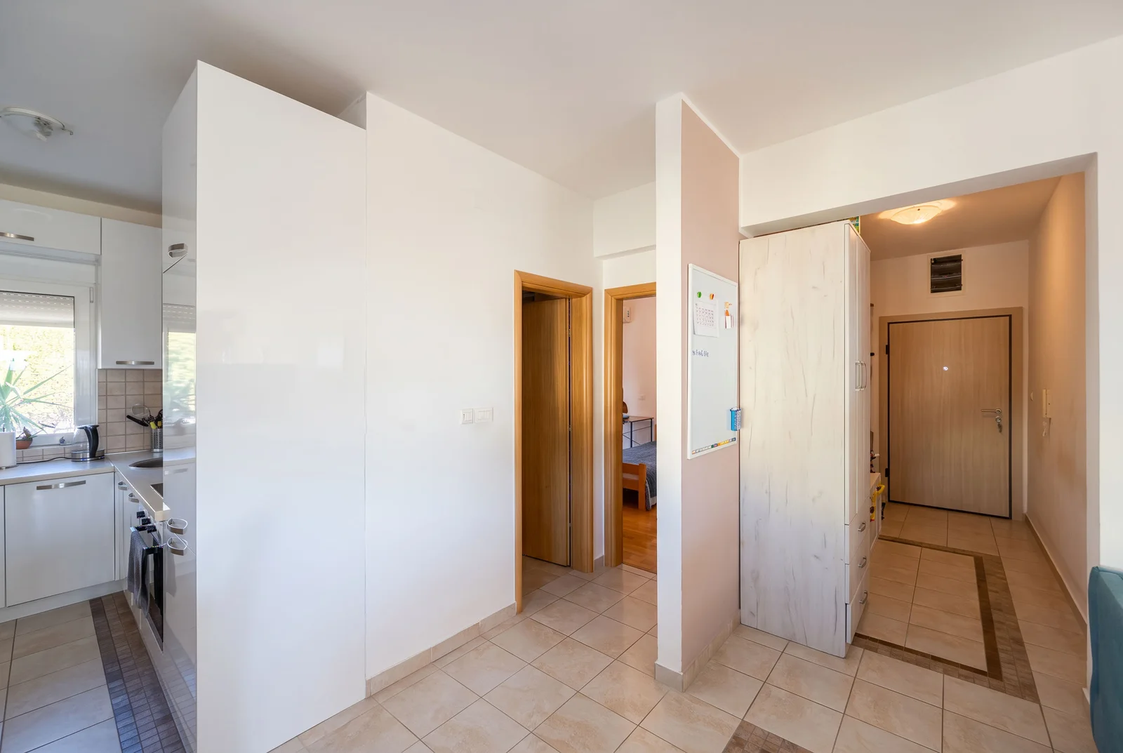 Hallway with a partial view of the kitchen on the left and a bedroom door in the background.