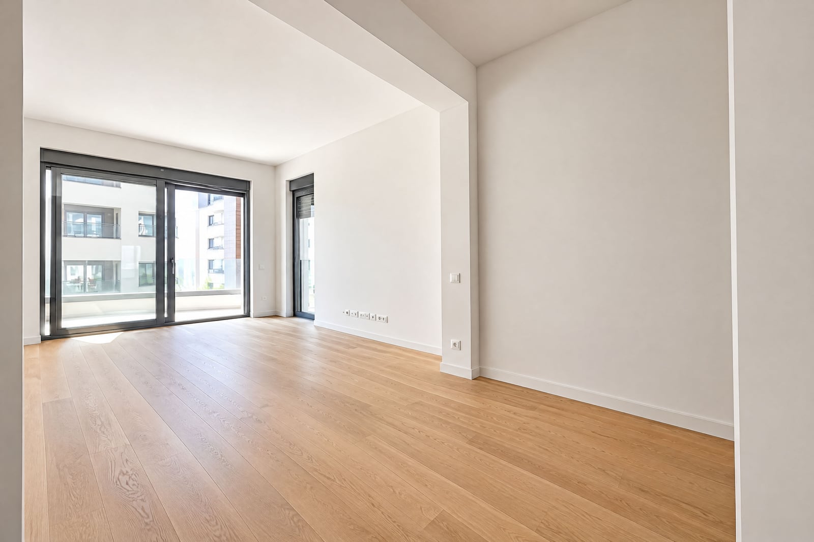 Empty room with light wood flooring and large glass sliding doors leading to a balcony.