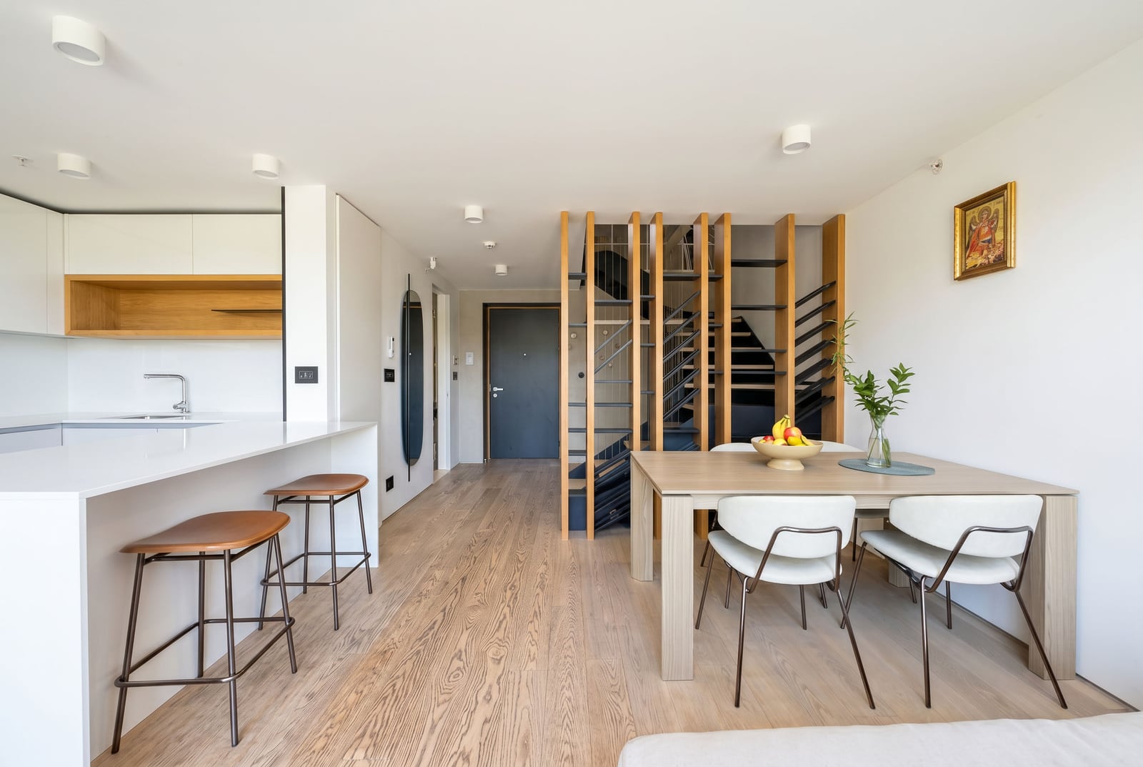 Modern kitchen-living room with a dining area and a staircase in an apartment, Budva, Montenegro. Bright interior, breakfast bar.