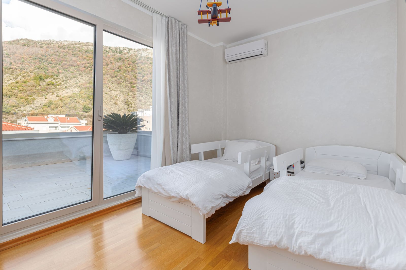 Children's bedroom with two beds and terrace access in a penthouse, Becici, Montenegro. Mountain and sea view.