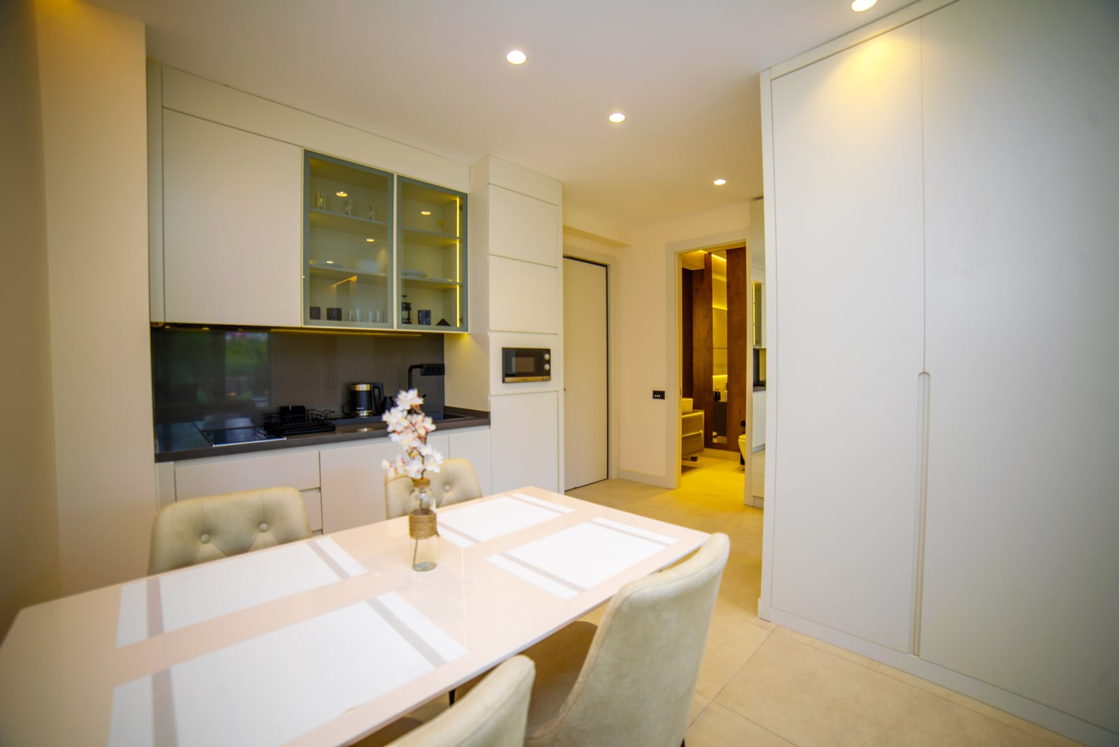 Modern kitchen-dining area in an apartment in Bečići, Montenegro: light-colored kitchen set, dining zone, and built-in appliances.
