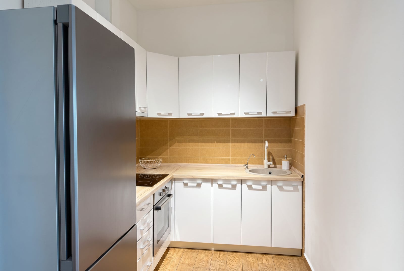 Modern kitchen with white cabinetry and appliances in an apartment, Becici residential complex, Montenegro. Cozy interior with a backsplash.