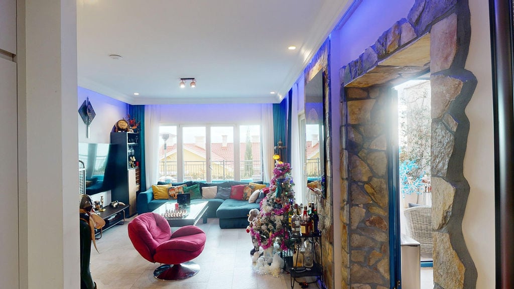 Living room with blue lighting and a stone portal in a townhouse, Luštica, Montenegro: soft furniture and a view of the terrace.