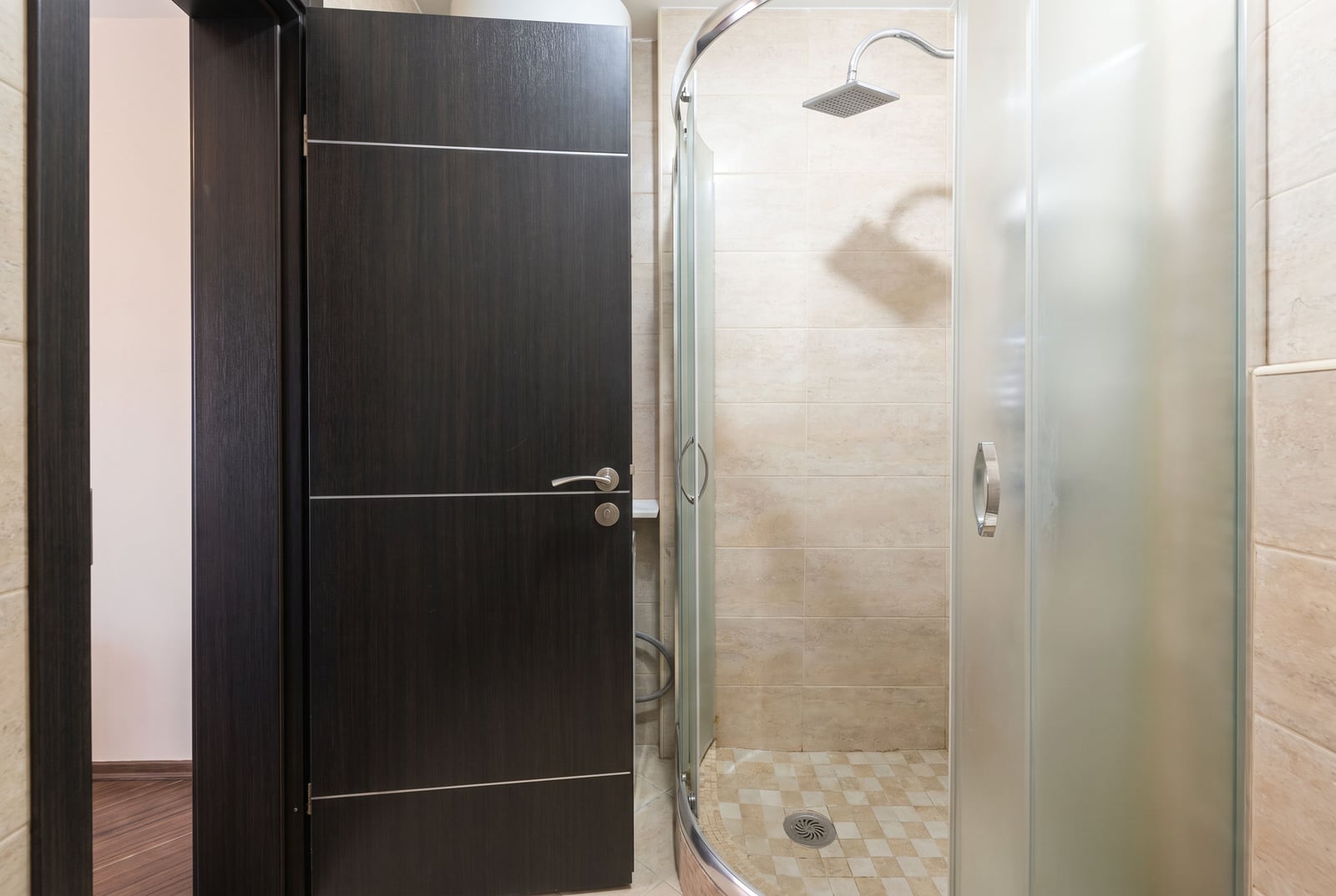 Modern bathroom with a shower enclosure and a dark interior door in an apartment in Budva, Montenegro