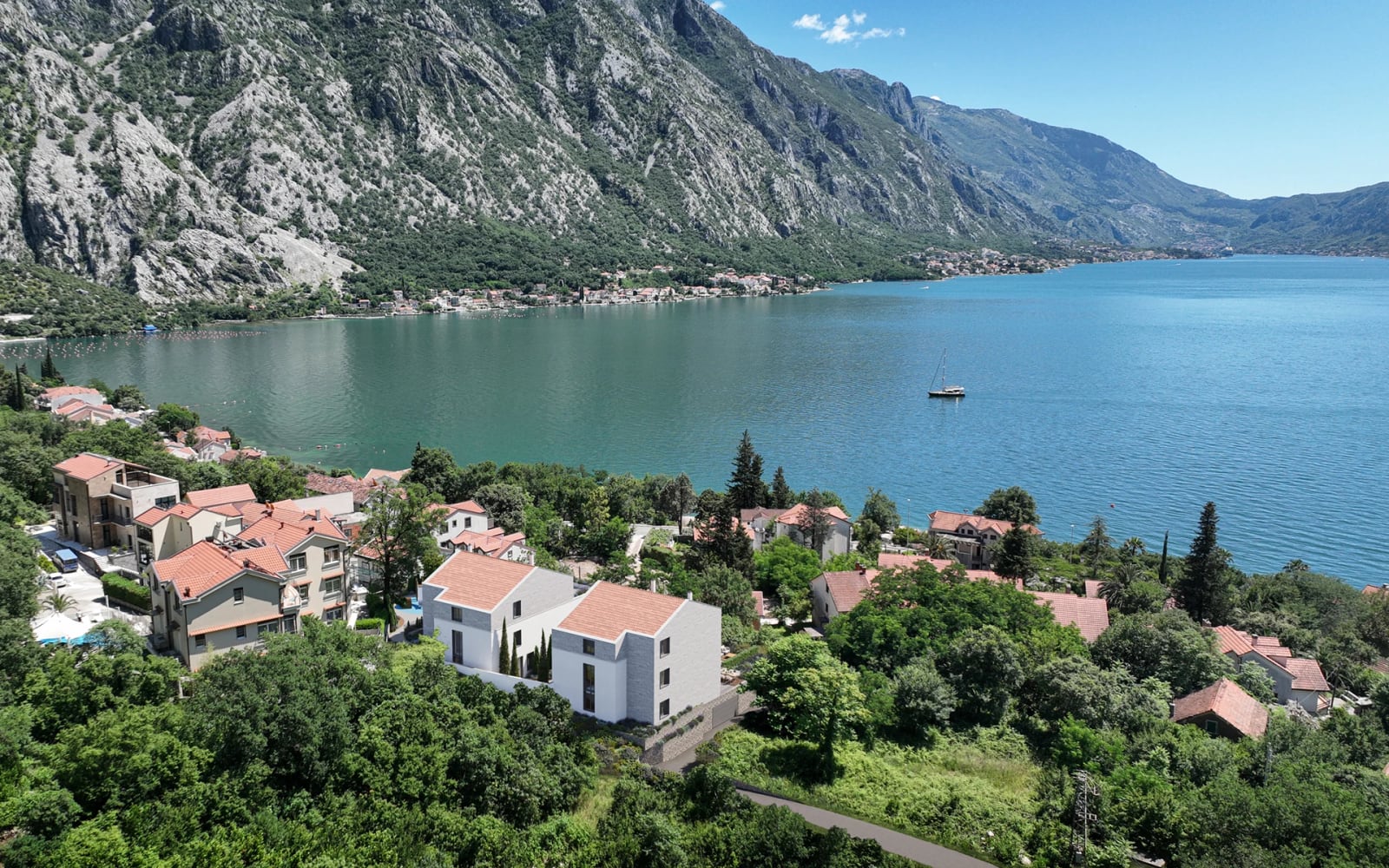 Aerial view of modern houses with tiled roofs and panoramic views of the Bay of Kotor in Orahovac, Montenegro.