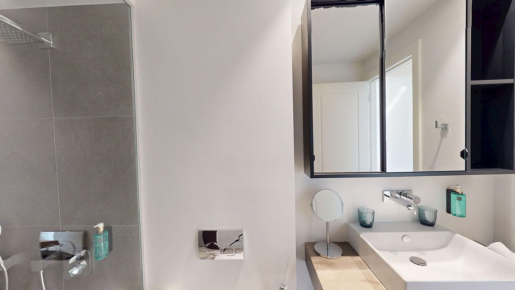 Modern bathroom in an apartment, Luštica, Montenegro: gray porcelain tile, shower cabin, and a stylish sink.