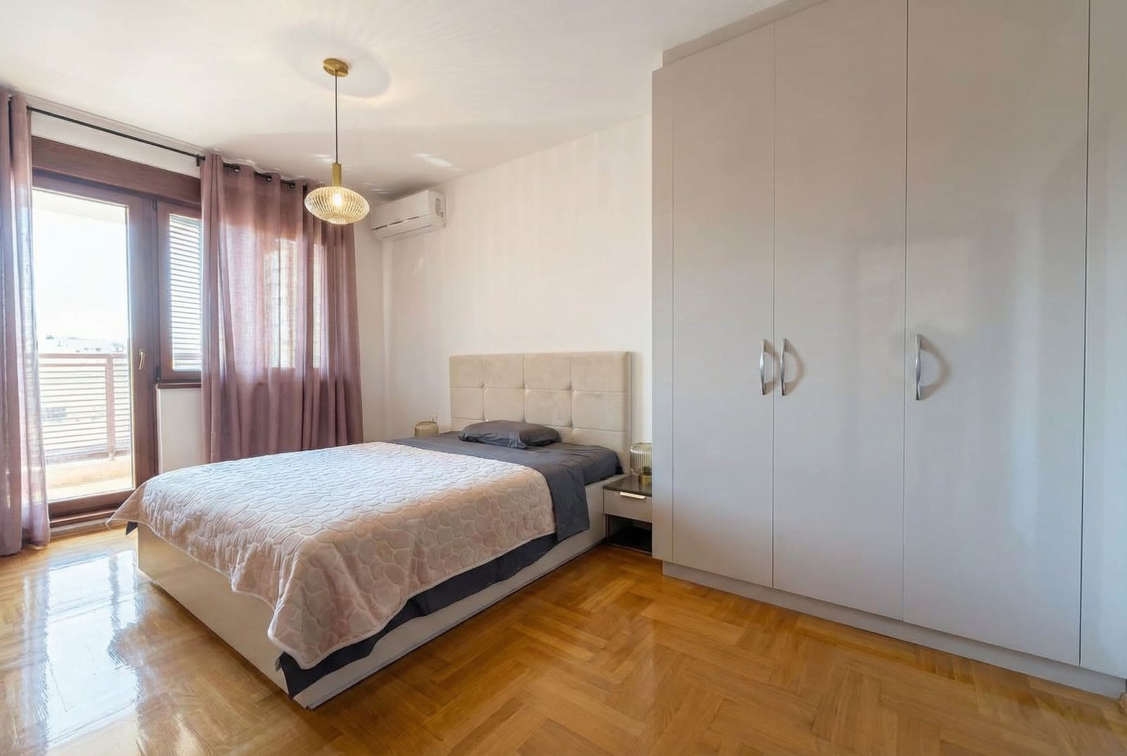 Bright bedroom with a double bed and a wardrobe in an apartment in Becici, Montenegro, with access to a balcony.