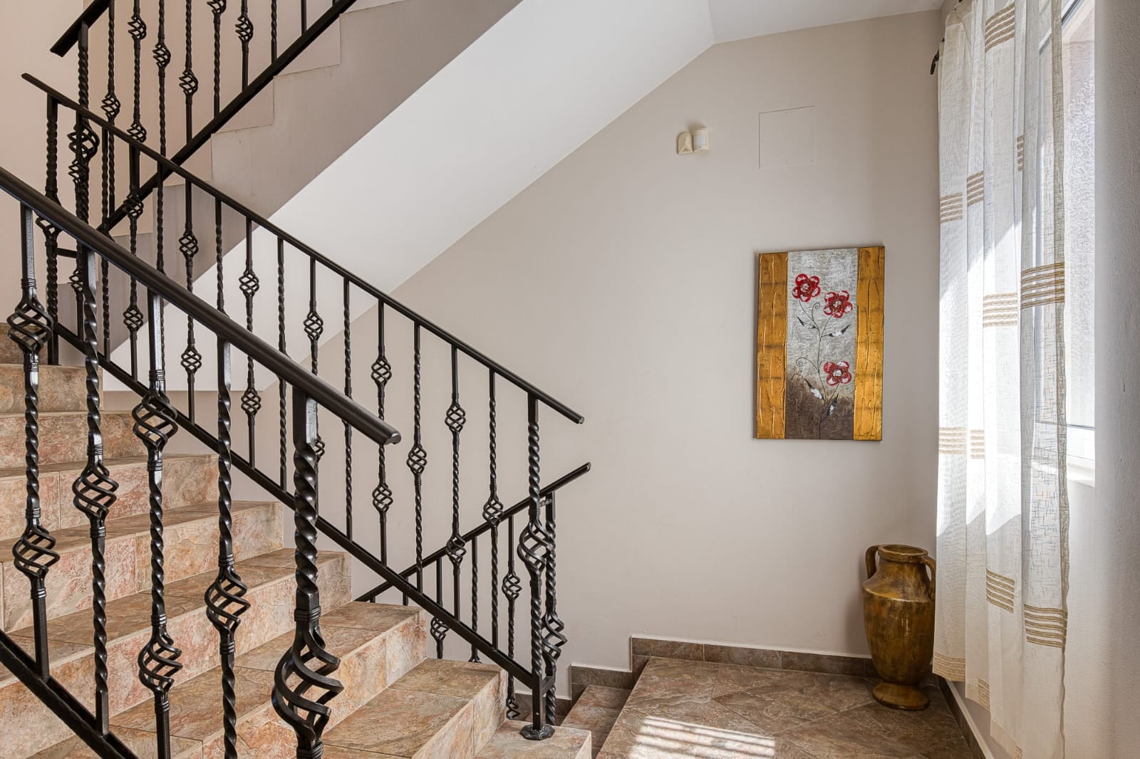 Staircase with wrought iron railings and ceramic tiles in a villa interior in Bečići, Montenegro.